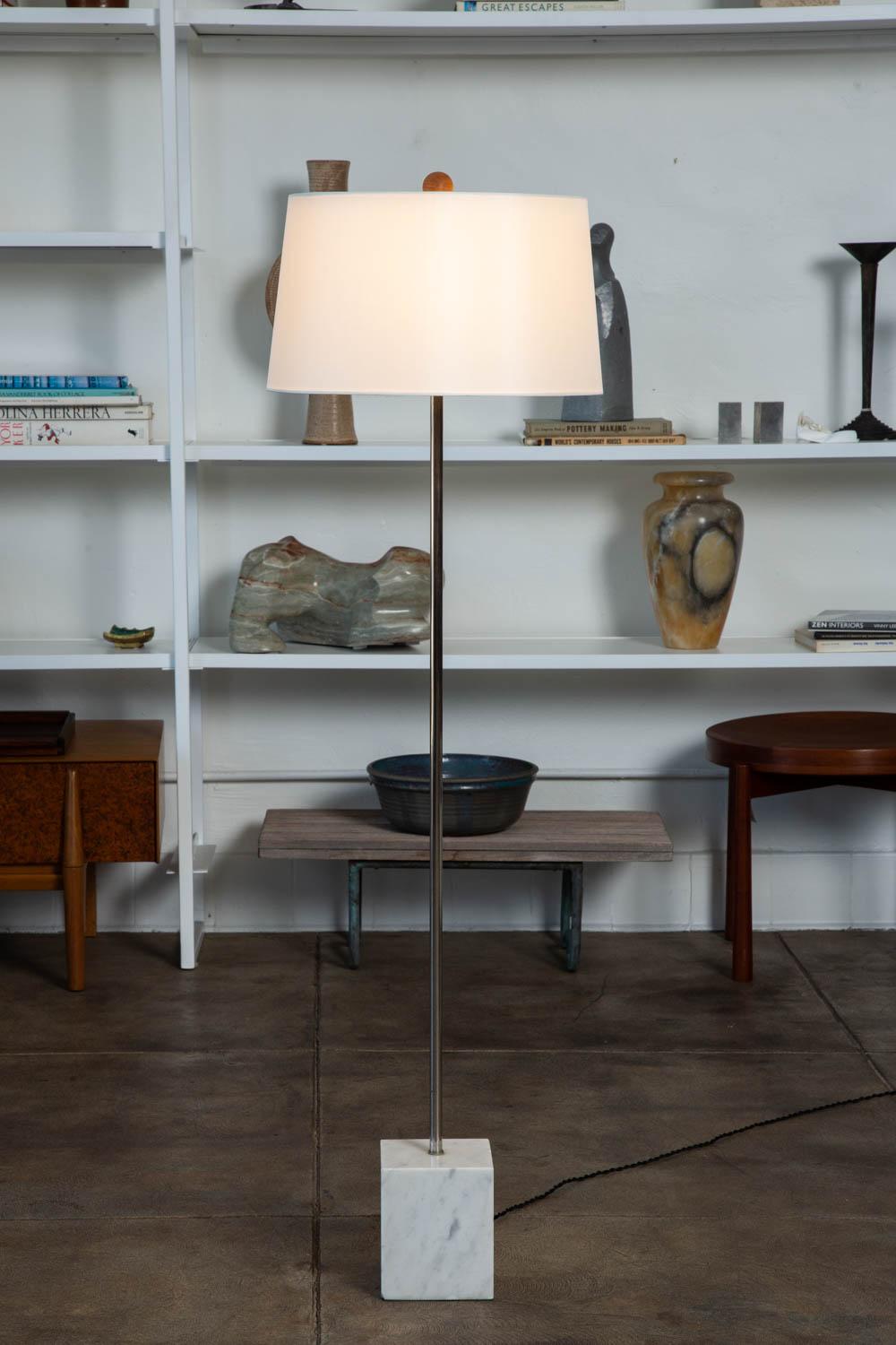 Metal floor lamp with marble base by Laurel Lamp Co. The lamp features a chromed steel stem, with a three bulb socket and a square Carrara marble base. The lamp has a new custom silk lamp shade with oak finial, and has been newly rewired with