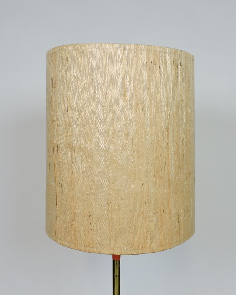 Very cool and unusual floor lamp made by high quality lighting manufacturer, Laurel Lamp Company of Newark, NJ. This well-made lamp has a tripod orange metal base, a brass tone stem and the original woven shade. It takes a 3-way standard base bulb