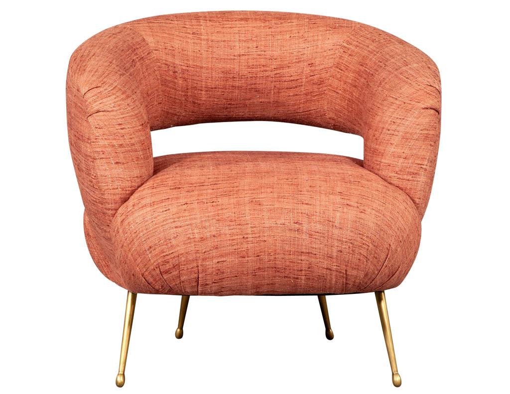 Laurel lounge chair by Kelly Wearstler. Inspired by Kell's signature soufflé chair shape, the Laurel lounge chair features a dramatic swooping curved back with tight upholstered seat. It rests on tapered cast brass legs in a burnished bronze and