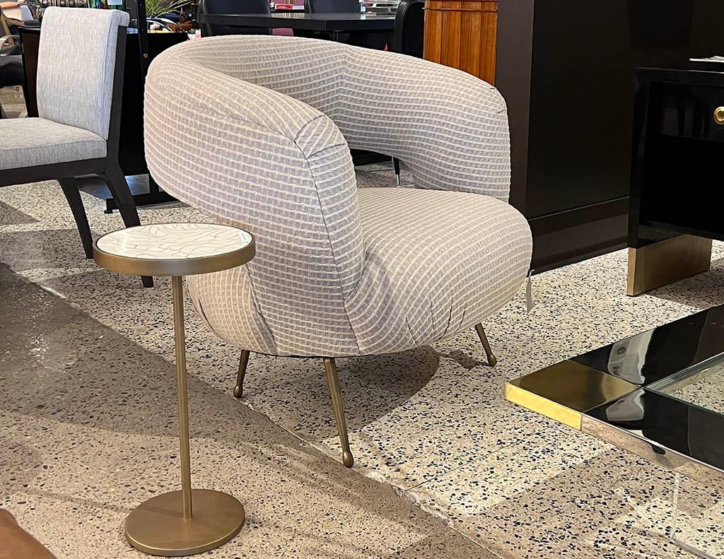 Laurel lounge chair by Kelly Wearstler. Inspired by Kell's signature soufflé chair shape, the Laurel lounge chair features a dramatic swooping curved back with tight upholstered seat. It rests on tapered cast brass legs in a burnished bronze and