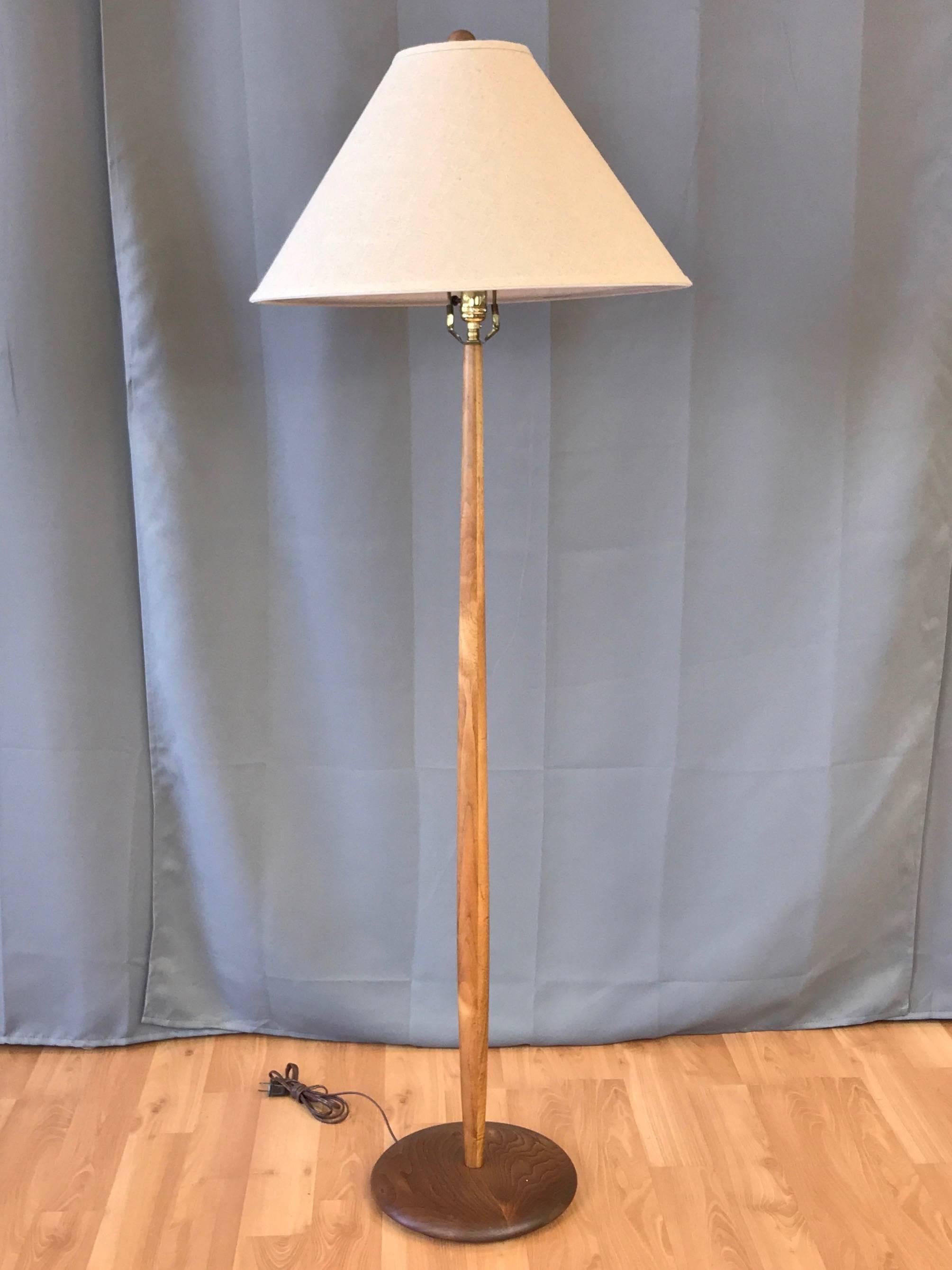A 1960s rare and well crafted solid walnut floor lamp by Laurel Lamp Company.

Sleek stem gently tapers to a slender point at either end. Disc-shaped base is smoothly sculpted and displays dynamically figured grain. With original walnut ball