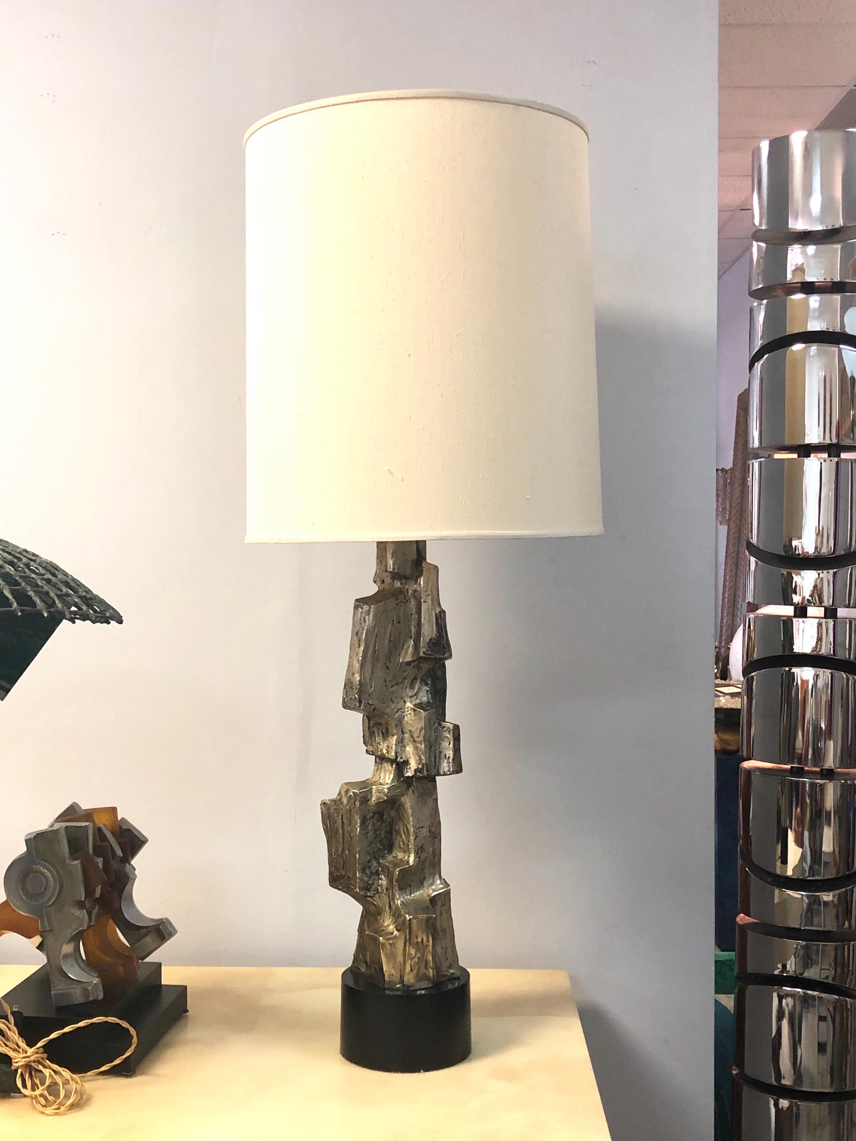 A large sculptural lamp by Laurel. Not the usual brown finish, this one has an old silver look. Retains original shade and finial.