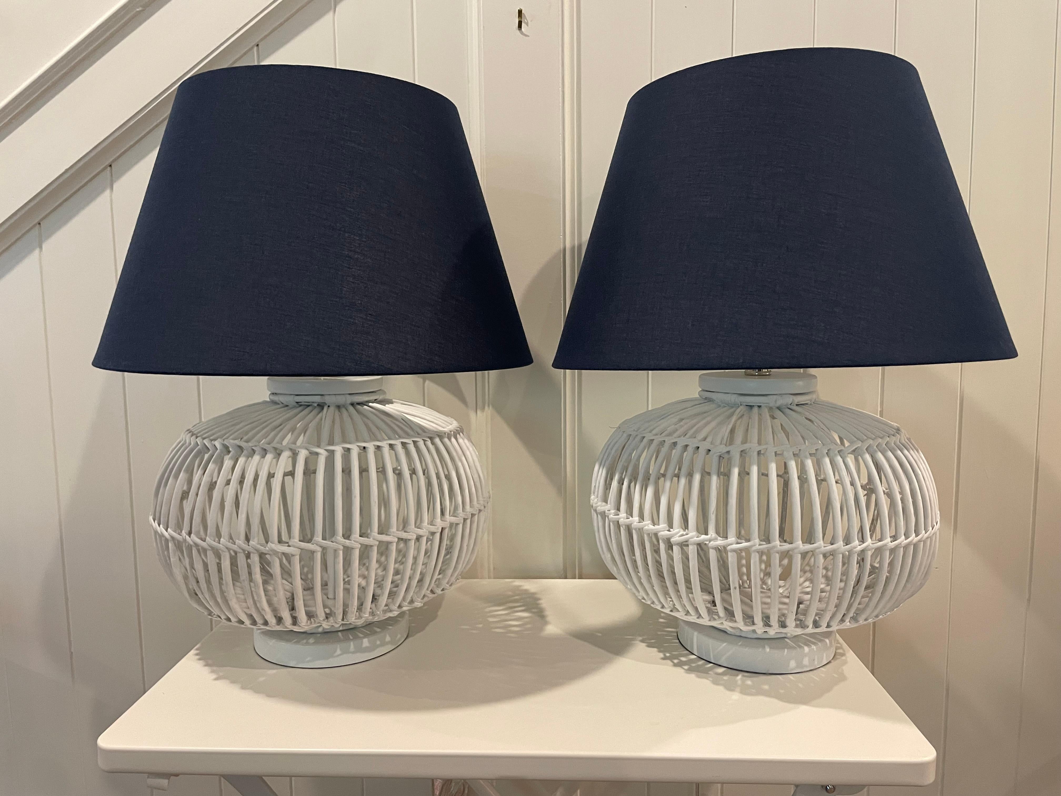 Pair of very attractive coastal style table lamps by Lauren Ralph Lauren. Elaborate hand bent and painted rattan with crisp navy shades and gold finials, the perfect lamps for a beach house, sunroom or for a chic look. The lamps are 14