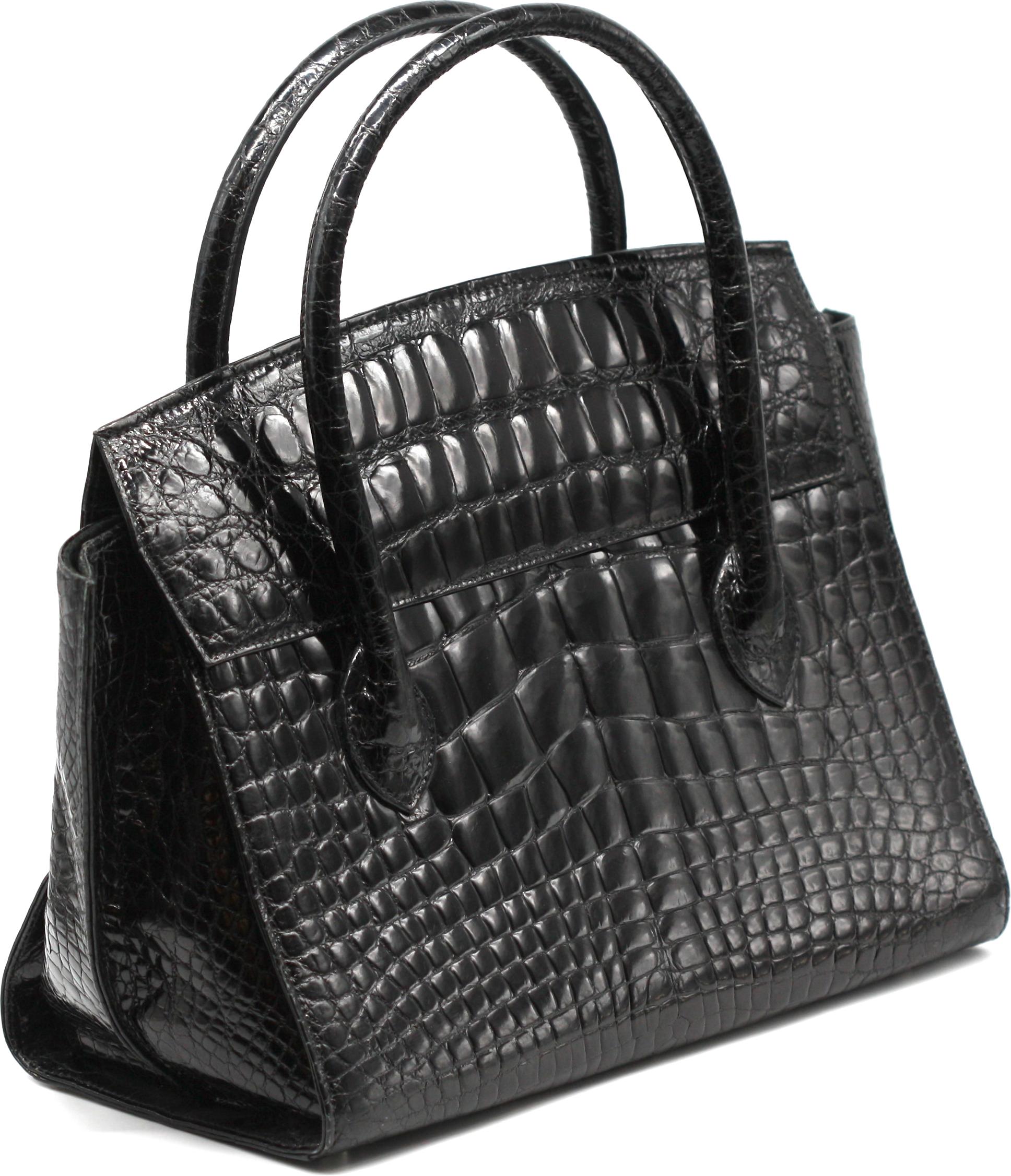 Laurent Effel Sac à main en alligator noir

De forme élégante et structurée, ce sac à main est finement réalisé en alligator noir brillant, les côtés étant surpiqués pour se projeter vers l'extérieur dans un détail architectural subtil. Fermé par un