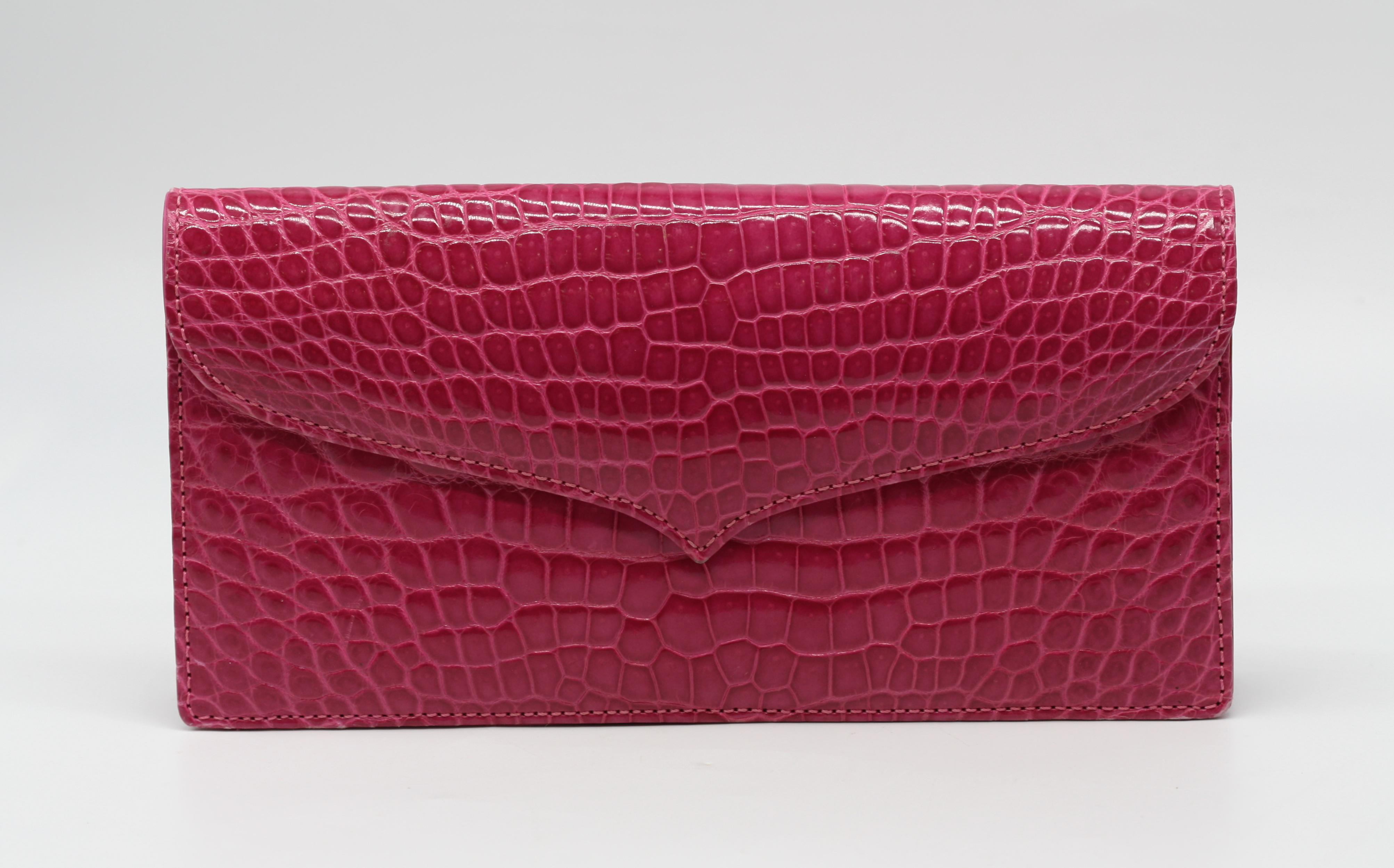 Pochette Laurent Effel in alligatore fucsia
Rettangolare, con una patta sagomata con chiusura a scatto, l'interno foderato in pelle con una tasca aperta e una con cerniera.
 Altezza 4,75 pollici, larghezza 9,75 pollici, profondità 1,5
