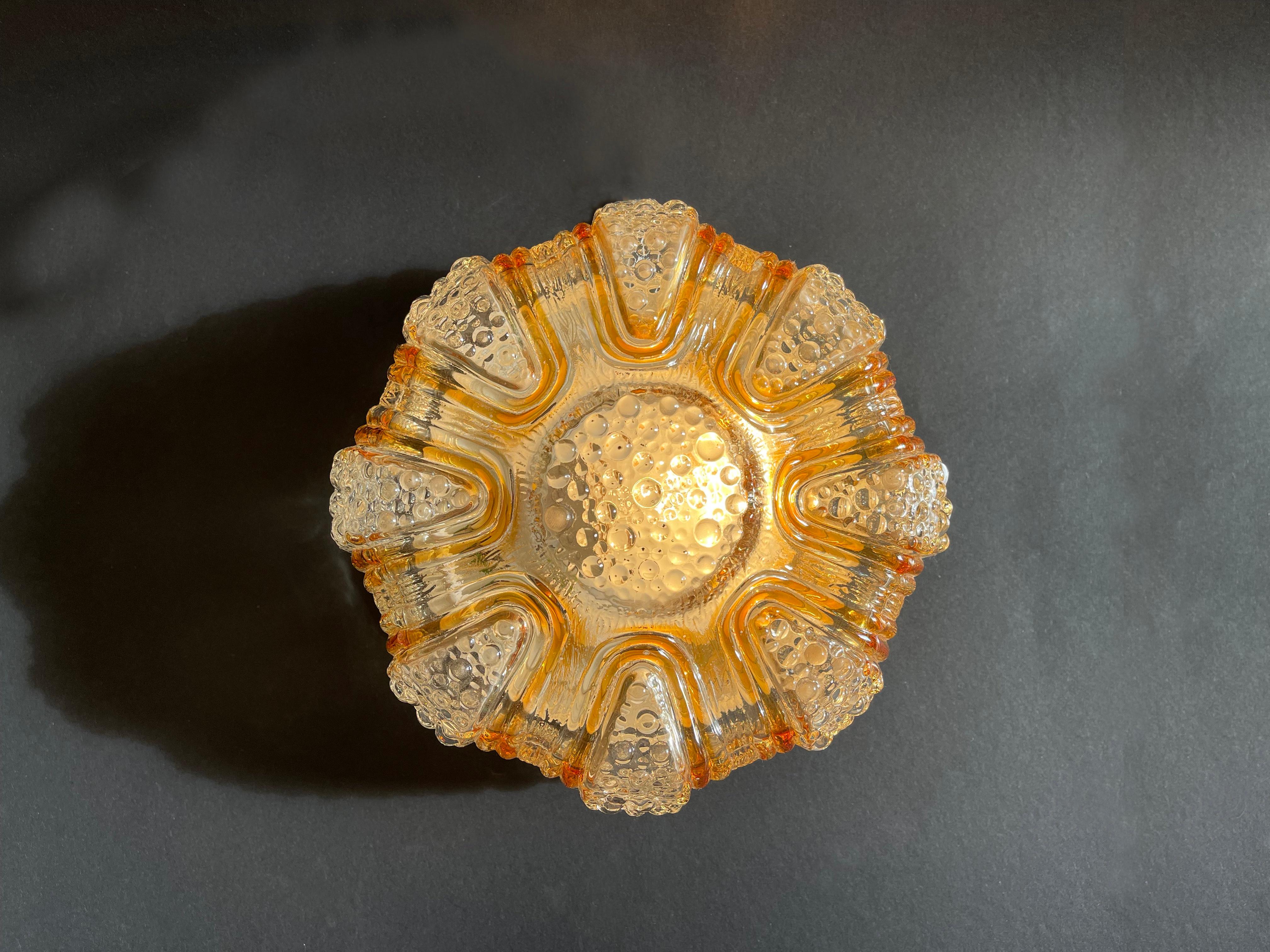 Beautifully designed wall or ceiling lamp in the style of Finnish mid-century artist Helena Tynell.
Amber & gold coloured 'lava stream' running down the sides past bubbles arranged in a round shape, sitting on a flush mount metal base.
Fantastic