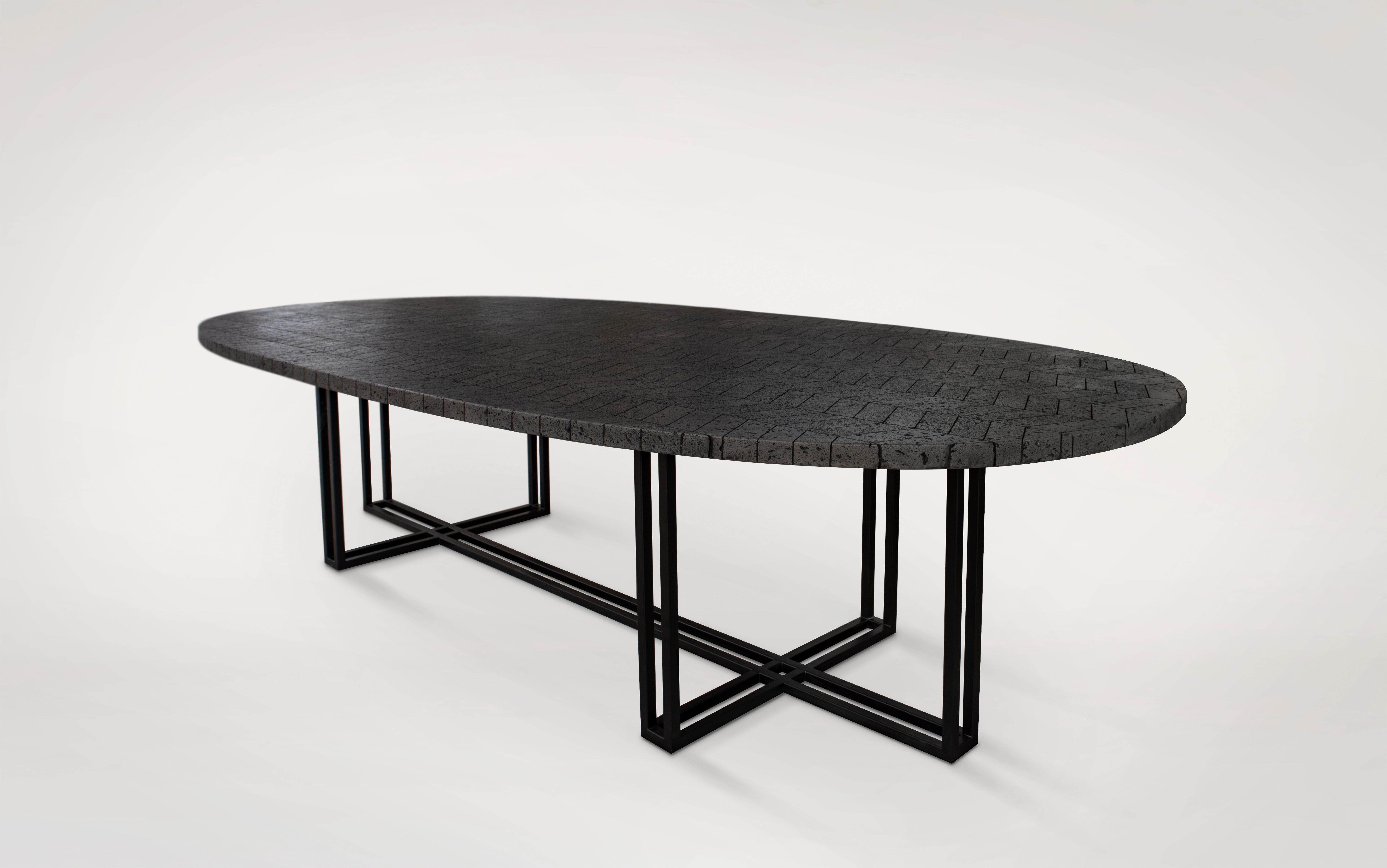 The vast volcanic stone stretches across an oval top featuring a composition of hand-cut, polished and mounted pieces. The metal base provides character and strength. The large-format Lava table is ideal for adding its energetic feel to both indoor