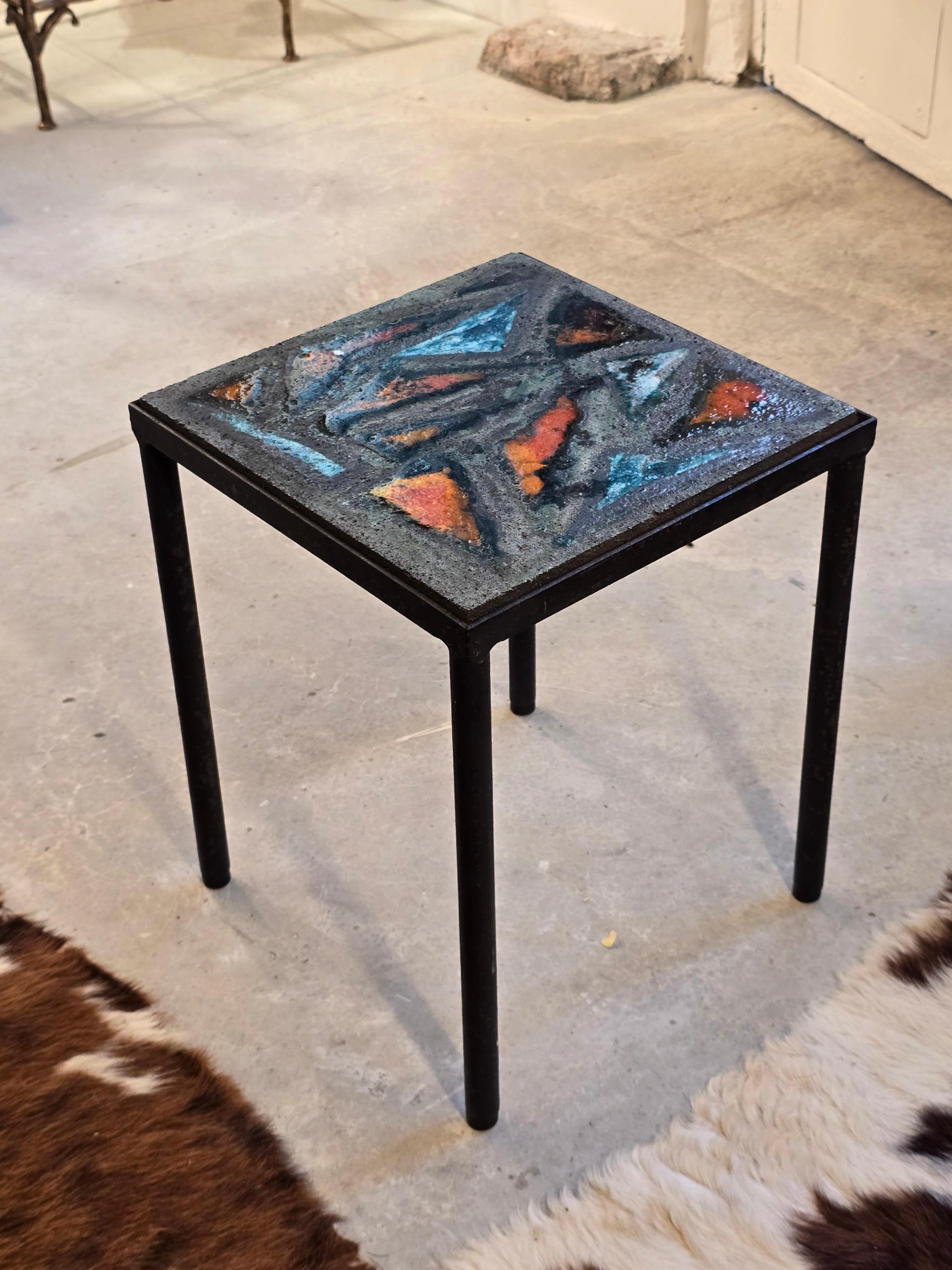 Table d'appoint carrée avec un plateau en pierre de lave émaillée, France, années 1960. La surface présente des motifs abstraits audacieux dans des teintes orange, turquoise et vertes vibrantes, fusionnés directement dans la pierre volcanique grâce