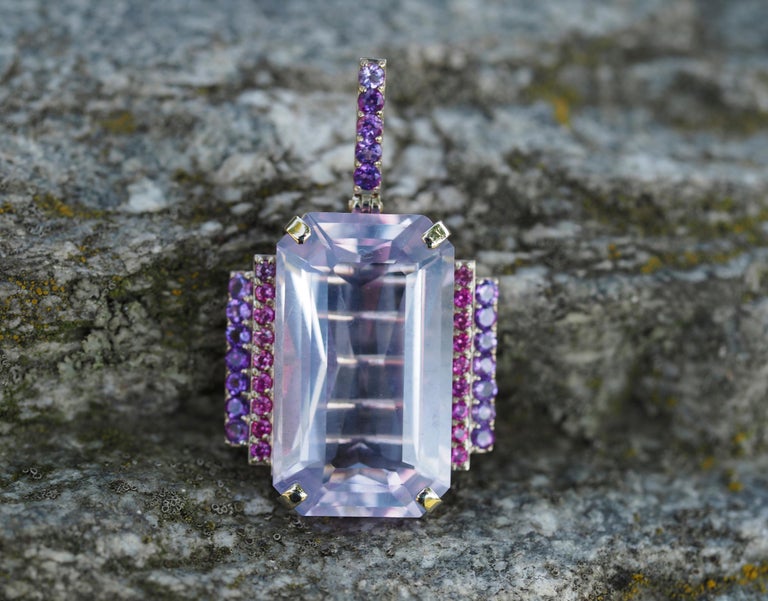 14 karat gold pendant with lavender amethyst , sapphires and amethysts

Weight: 7.9 g. 
Size: 35x20.85 mm
Set with amethyst, color -lavender
Emerald cut, 21 ct.  (22.93х13.46х9.34 mm)
Clarity: Transparent 

Surrounding stones  
- 18 sapphires: round