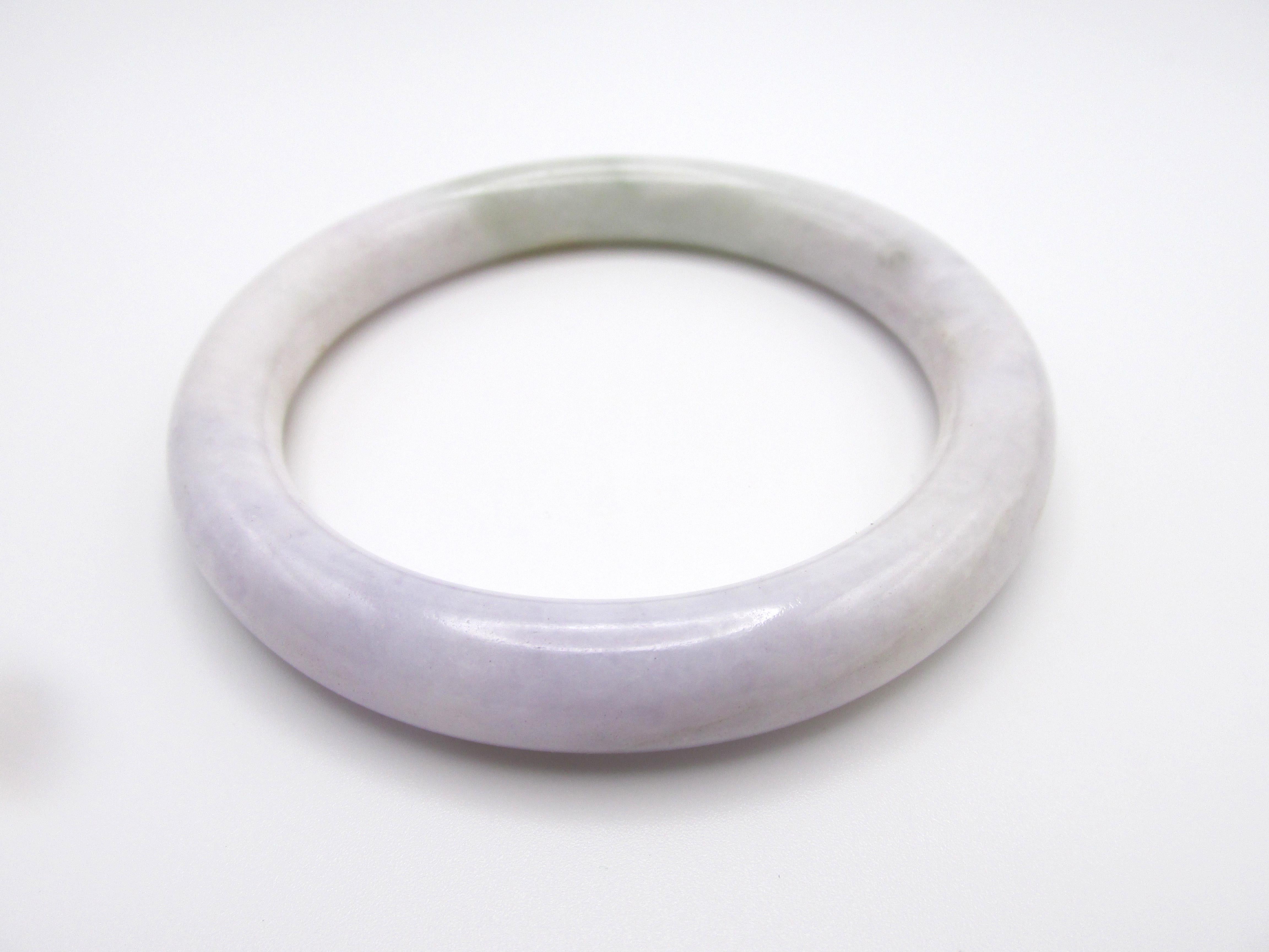 This large, jadeite bangle bracelet with an inner diameter of 61mm and a weight of 63.88 grams has beautiful subtle celadon and lavender coloring with a splash of brown.  Surface reaching inclusions.