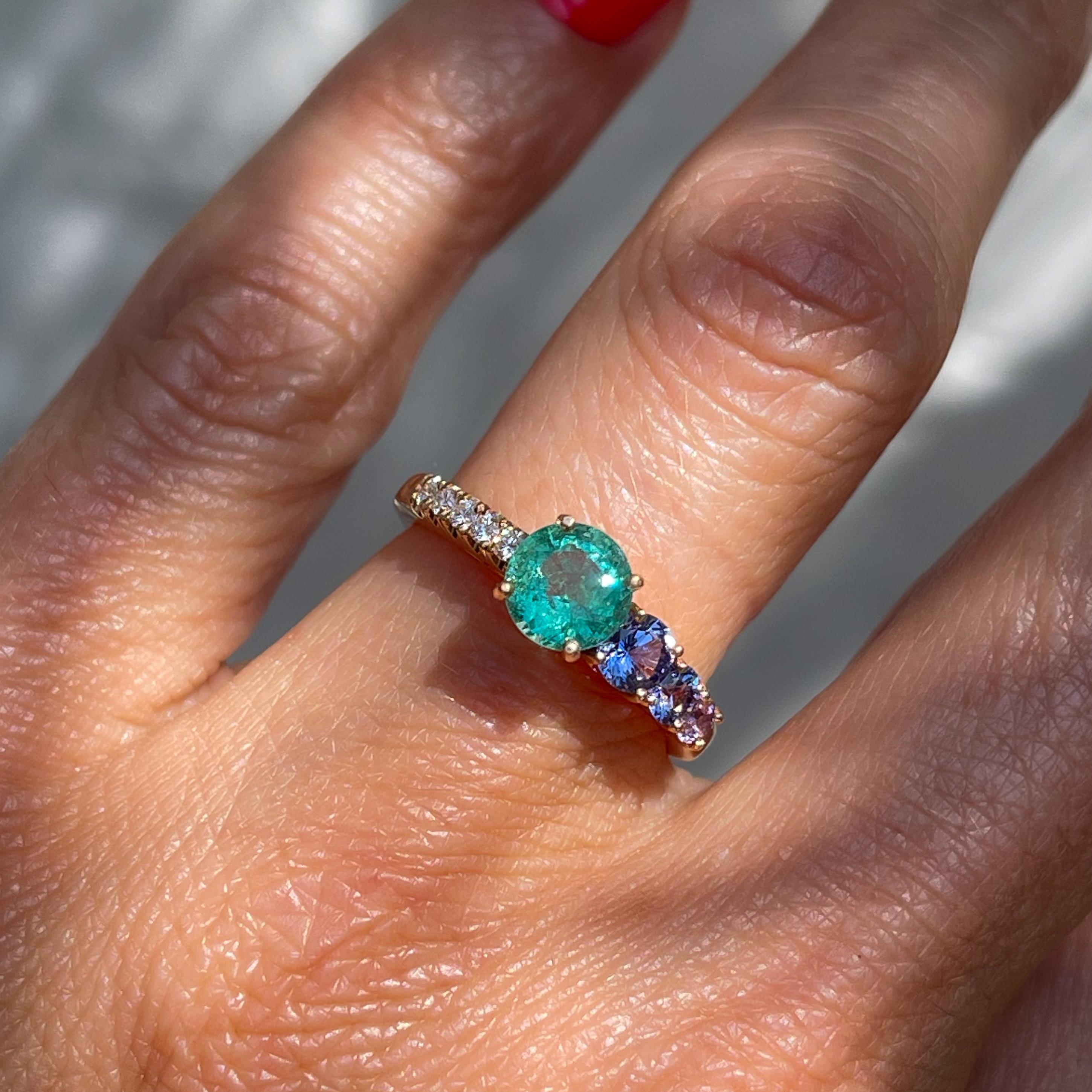 A tiered procession of exquisite color adorns this Colombian Emerald Ring. Flanked by purple sapphires and pave diamonds, the balanced asymmetry around the stunning green gem exacts a sublimely unique emerald ring design. The soothing vision,