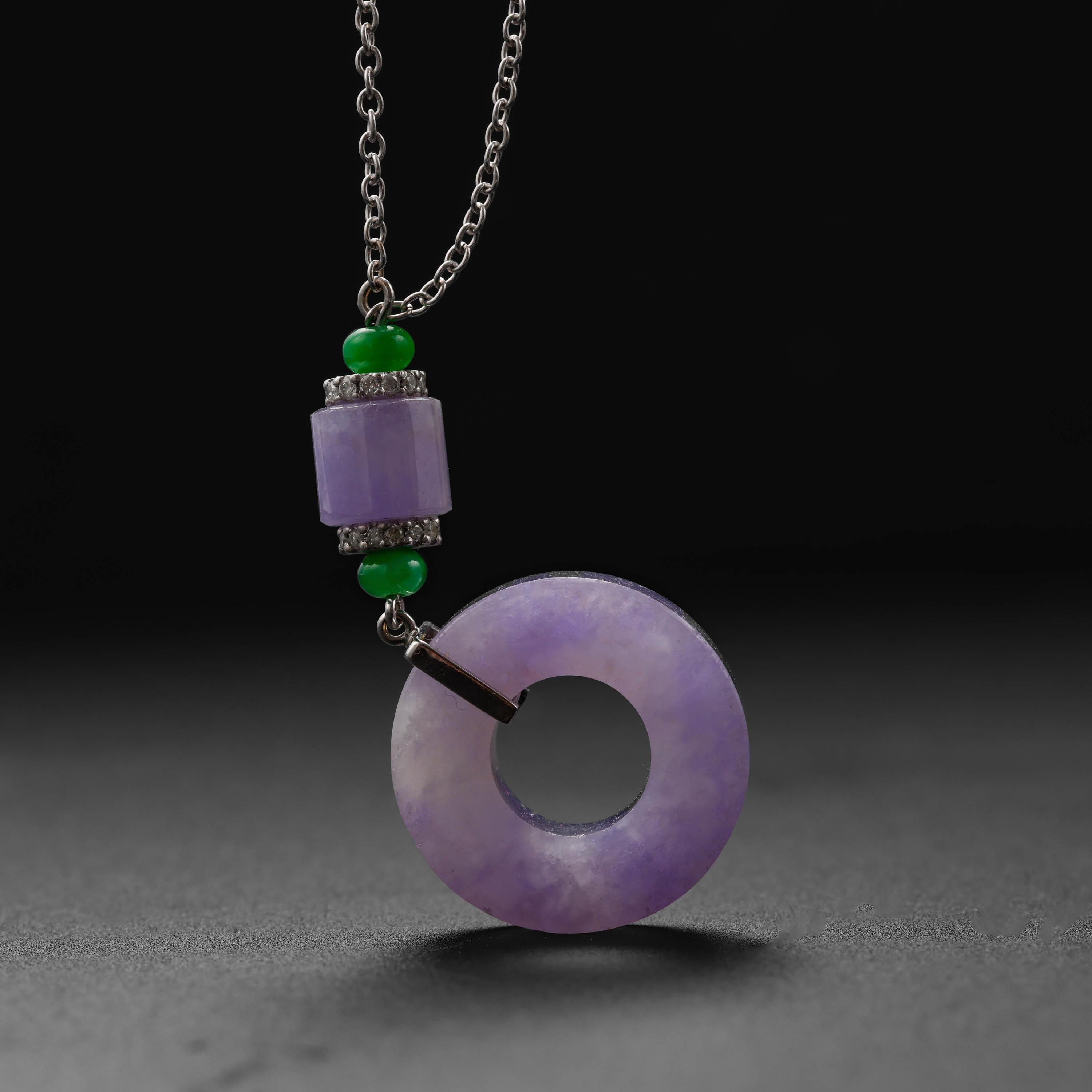 Utterly magnificent, this rich lavender jade pendant features a light purple Burmese jadeite circle that measures approximately 21mm x 5mm. The disk is suspended from a 14k white gold bail set with white diamonds, allowing the disk to dangle freely