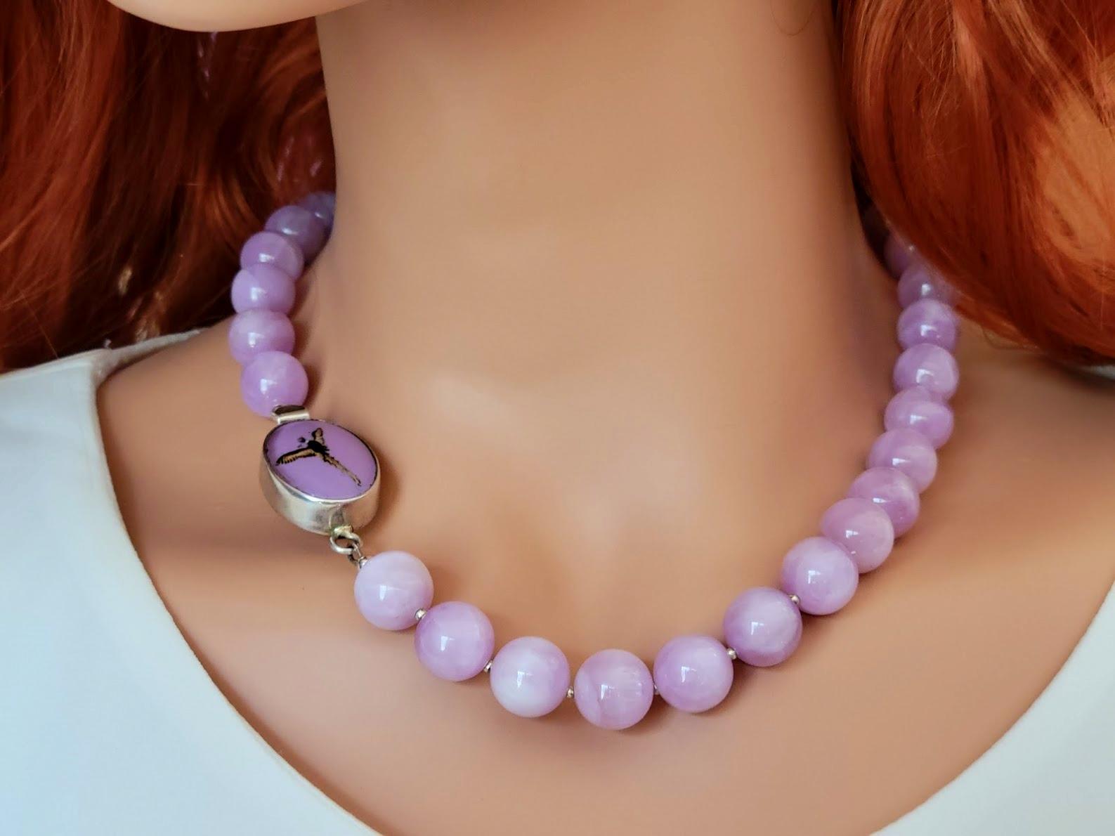 Lavender Chatoyant Kunzite Necklace With Vintage Painted Glass Essex Crystal Clasp.

The length of the necklace is 18.5 inches (47 cm). The size of the smooth round beads is 12.5 mm.
The color of the beads is a soft lavender with a slight cat's eye