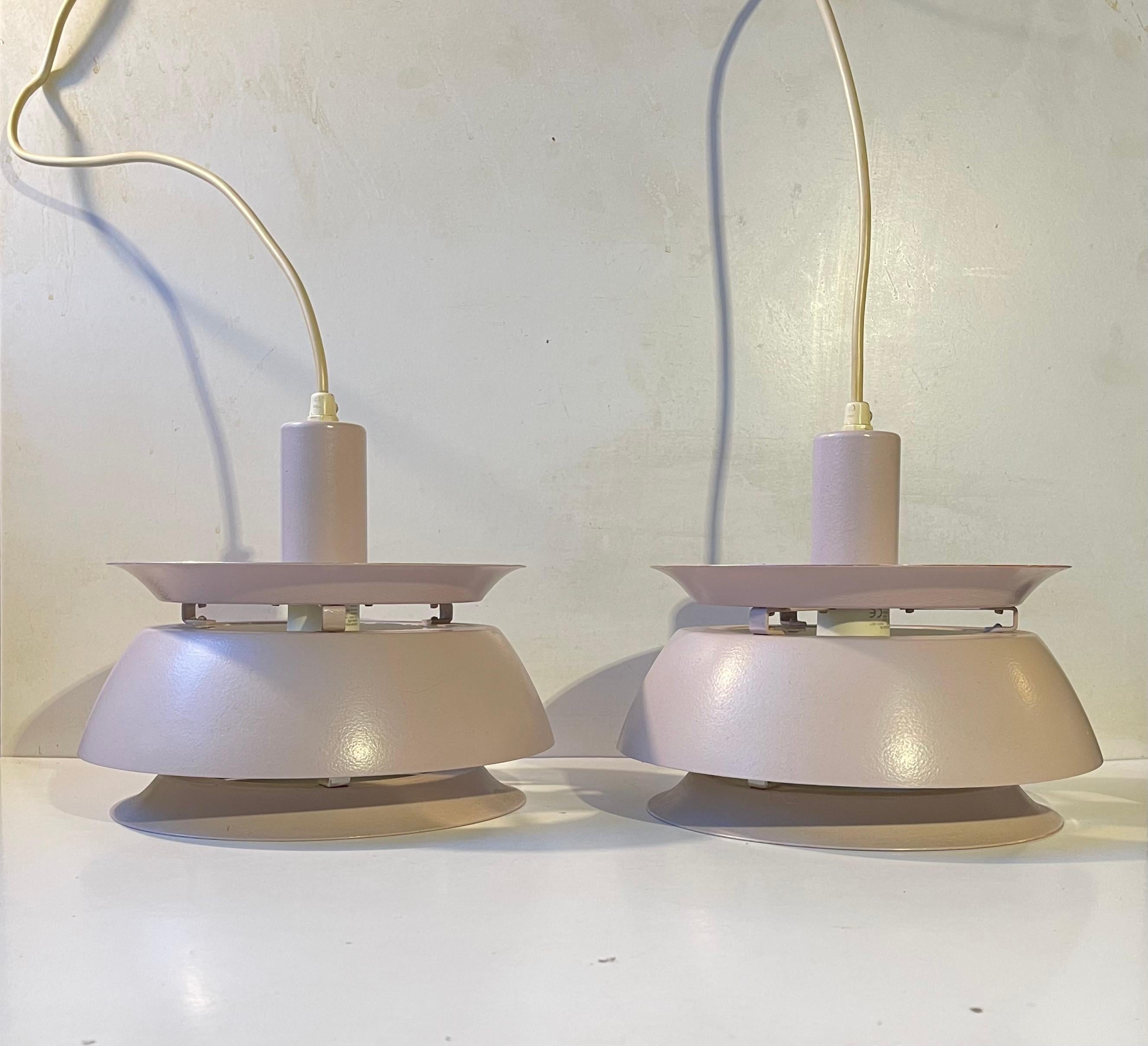 A pair multiple tiered aluminum pendant lights by Vitrika in Denmark. Designed and made during the early 1970s in a style reminiscent of Carl Thore and Jørn Utzon. The lights features white interior shades and a textured, possibly, refinished light