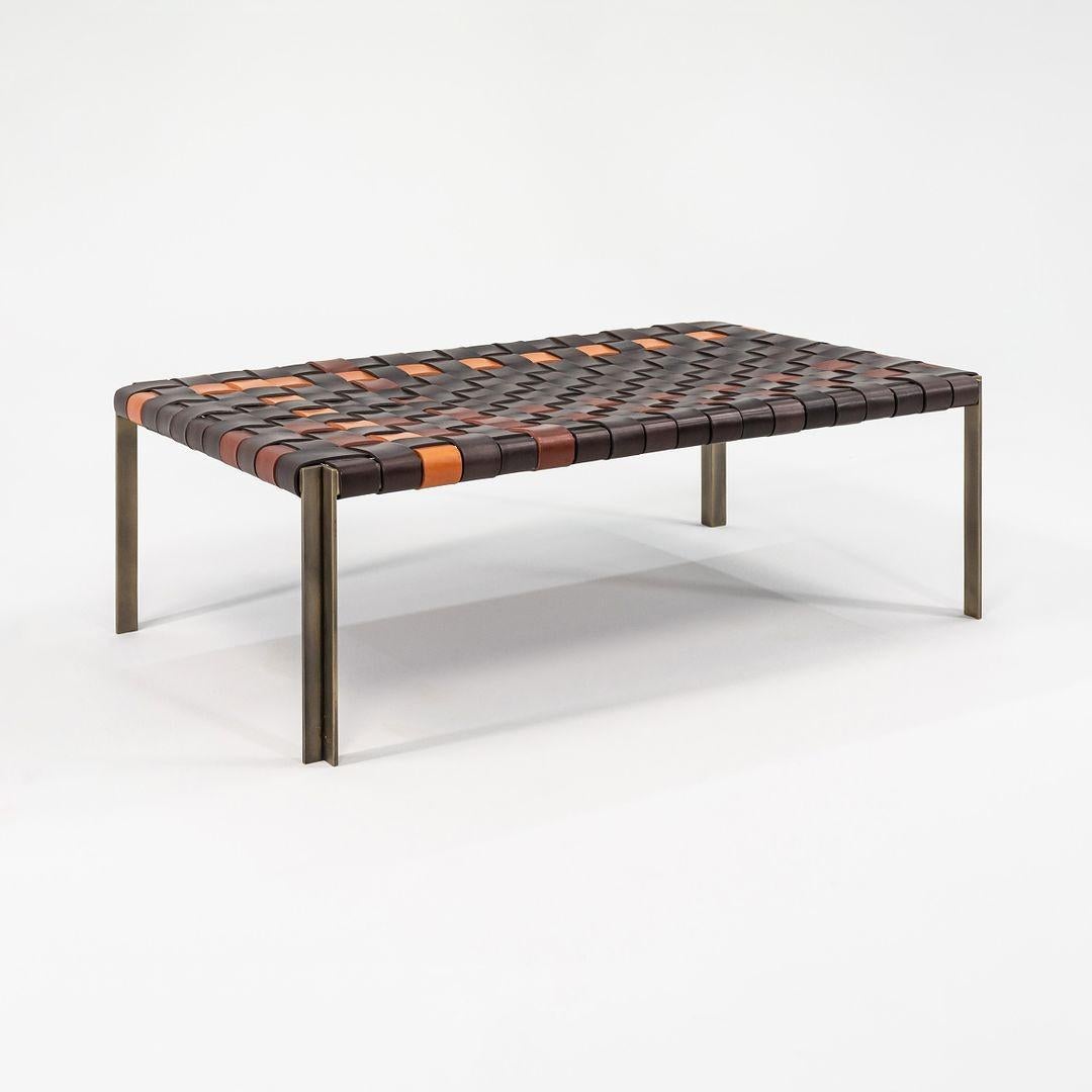 This is a TG-18 Small Woven Leather Bench in multiple brown leathers with a light antique bronze frame produced by Gratz Industries. The bench was designed was designed by Katavolos, Littell and Kelley in 1952 as part of the original Laverne