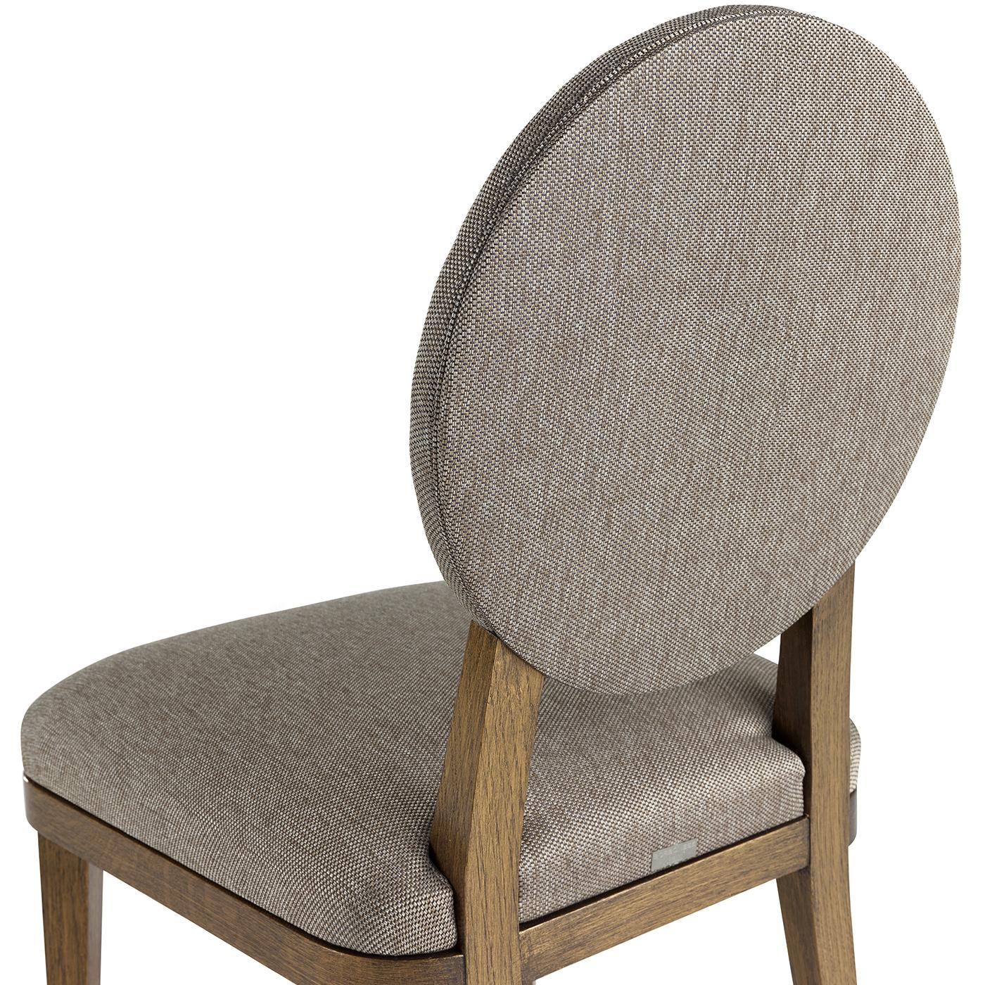 This elegant chair was crafted of solid durmast oak with a stunning finish that gives a unique bronzed brass effect to the natural grain of the wood of the four feet and the back structure connecting the seat with the oval backrest. The comfort of