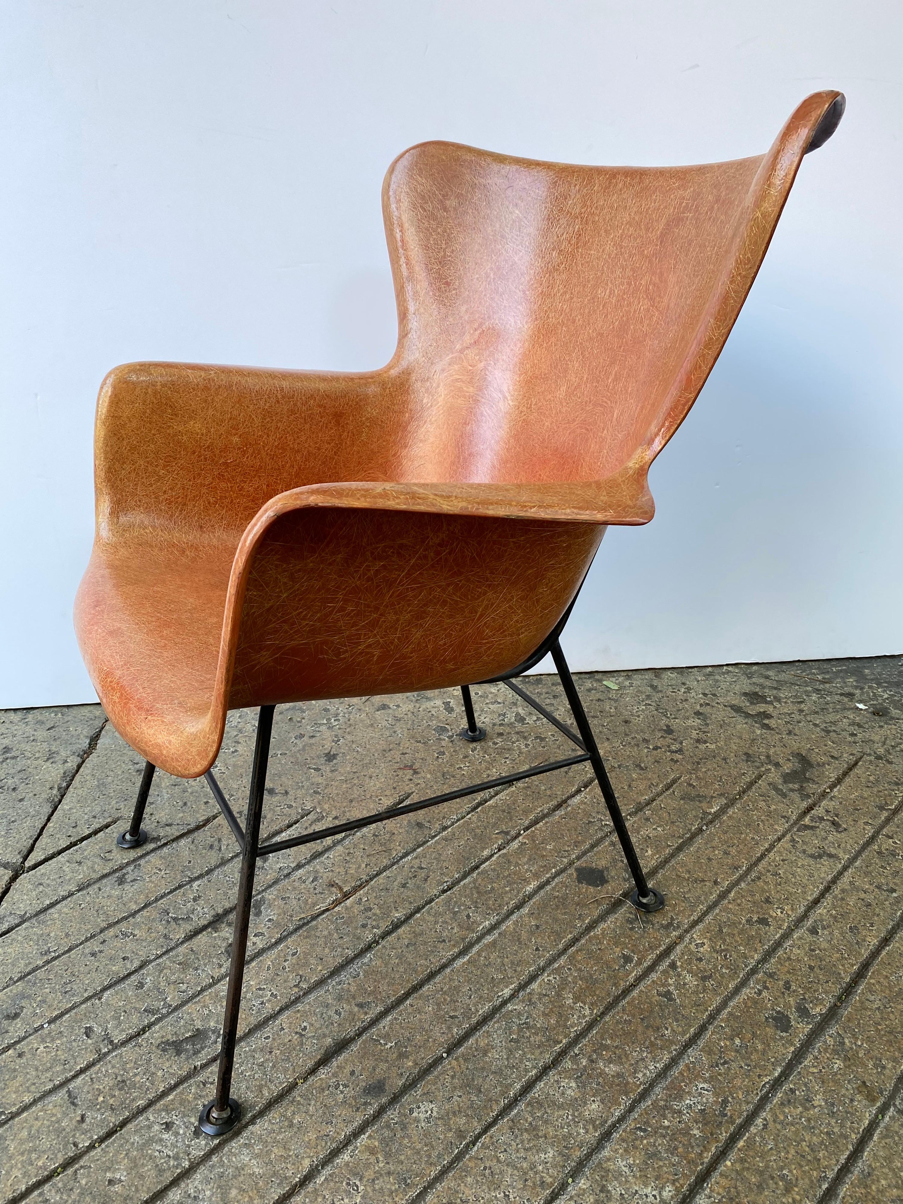 Lawrence Peabody fiberglass arm lounge chair. Nice shade of burnt orange with the more desirable wrought iron black base. Comfortable with a high back. Exposed black bushings visible from behind. Eames Technology used on a larger scale.