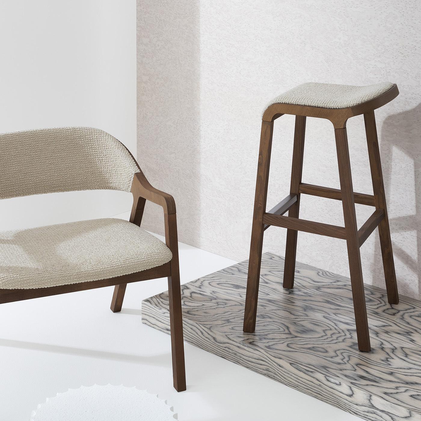 Este exquisito taburete es un complemento perfecto para decoraciones rústicas y modernas de tonos cálidos. Su armazón de fresno macizo está teñido de marrón caoba, tonalidad que conserva el encanto intemporal de las maderas de primera calidad e