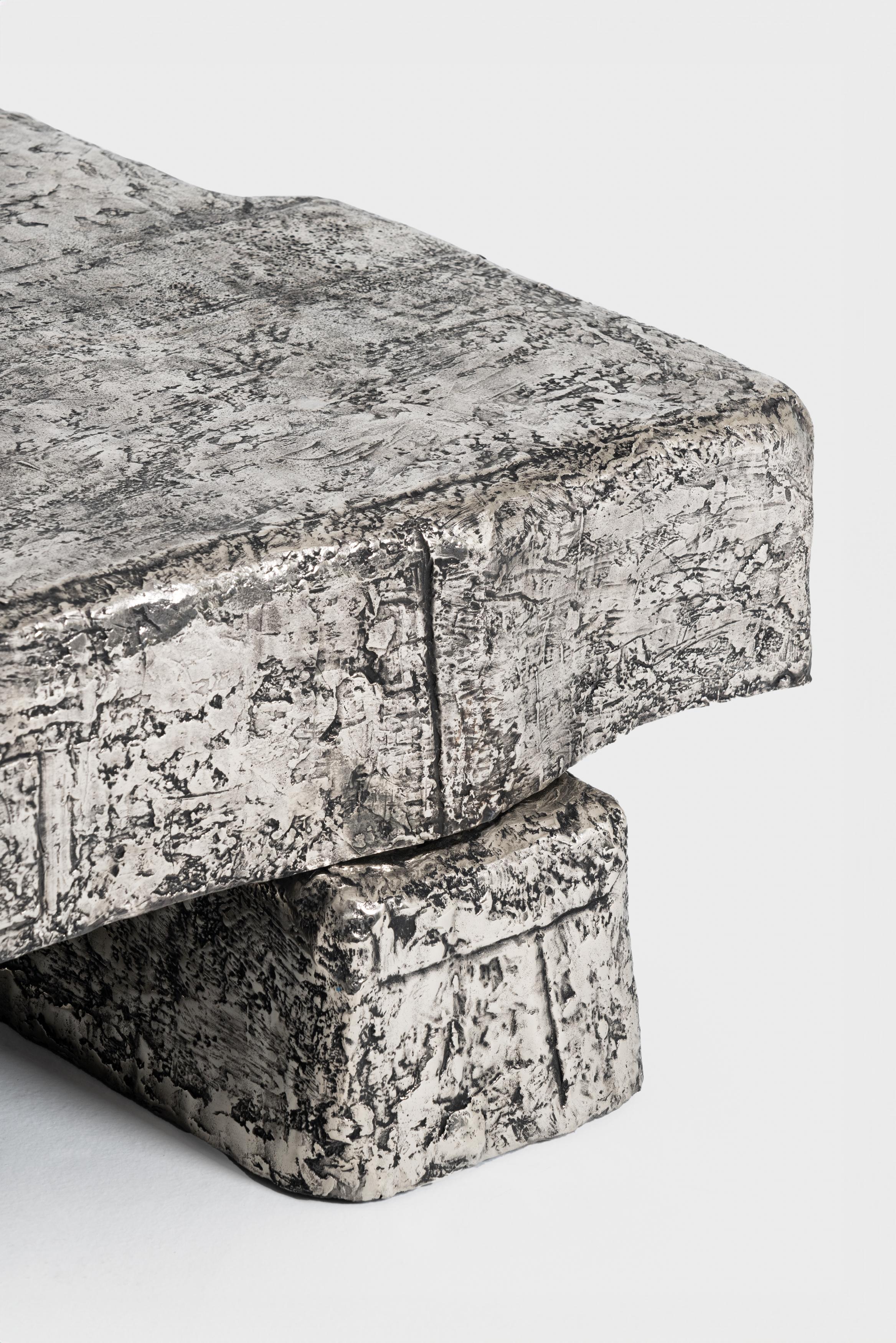 The Coffee Table, materialized in white bronze, shows a relief of solidifying
wax in which textile is dipped, then draped, in a fixed position. It is by placing
layer over layer, how slowly strength is increasing within the model.

The series  tells