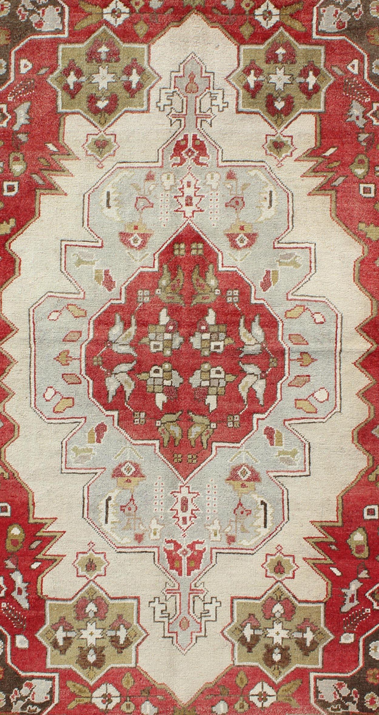 Measures: 4'4 x 7'9

This vintage Turkish Oushak rug features an intricate geometric medallion design. The central medallion is surrounded by multi-layers in the field. The various shades of red, green, pale blue, off white and light brown blend
