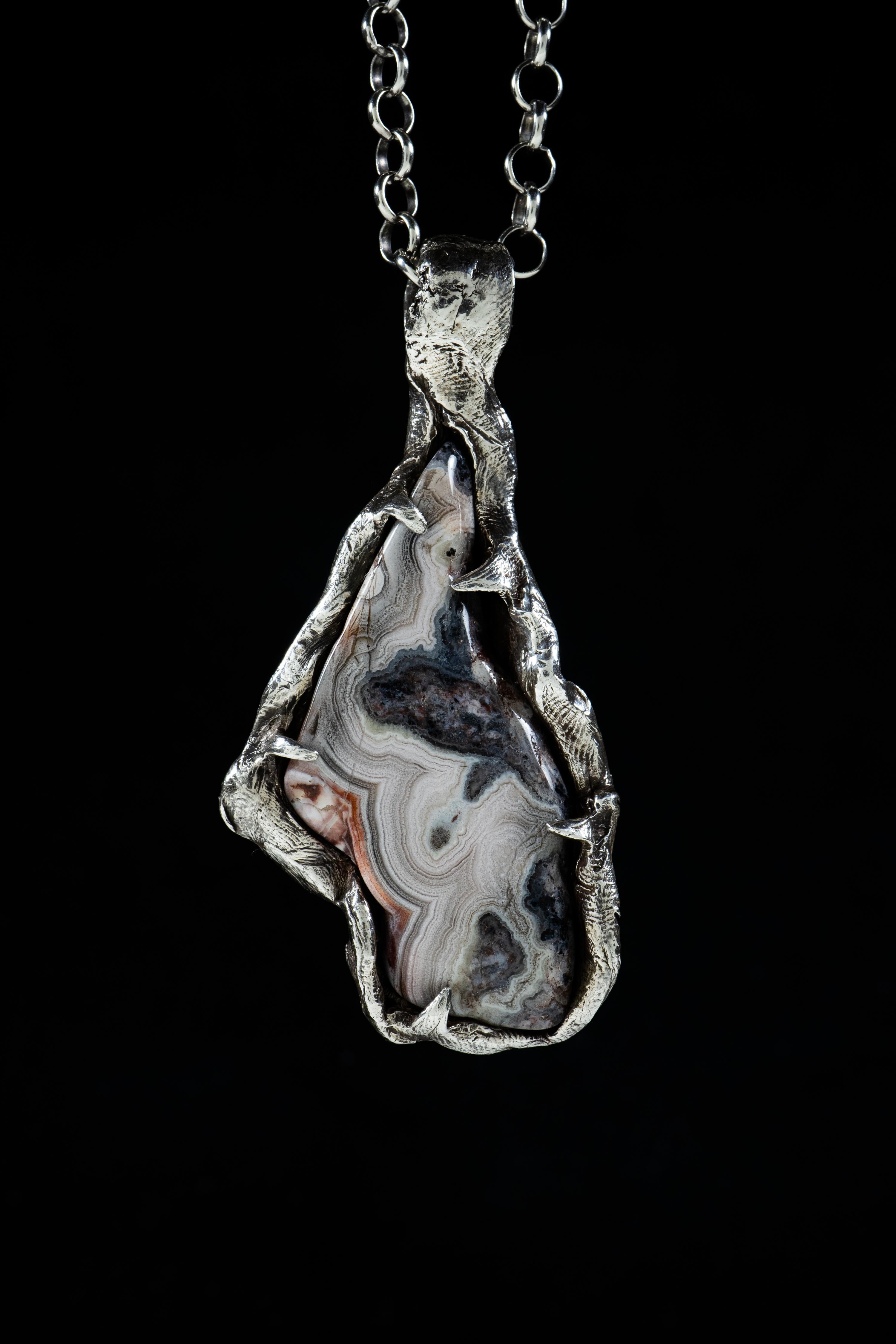 Layers of Space is a one-of-a-kind pendant by Ken Fury that is hand-carved, cast in sterling silver, and features a natural Agate stone.

Size: 76mm x 35mm

Hand-signed
