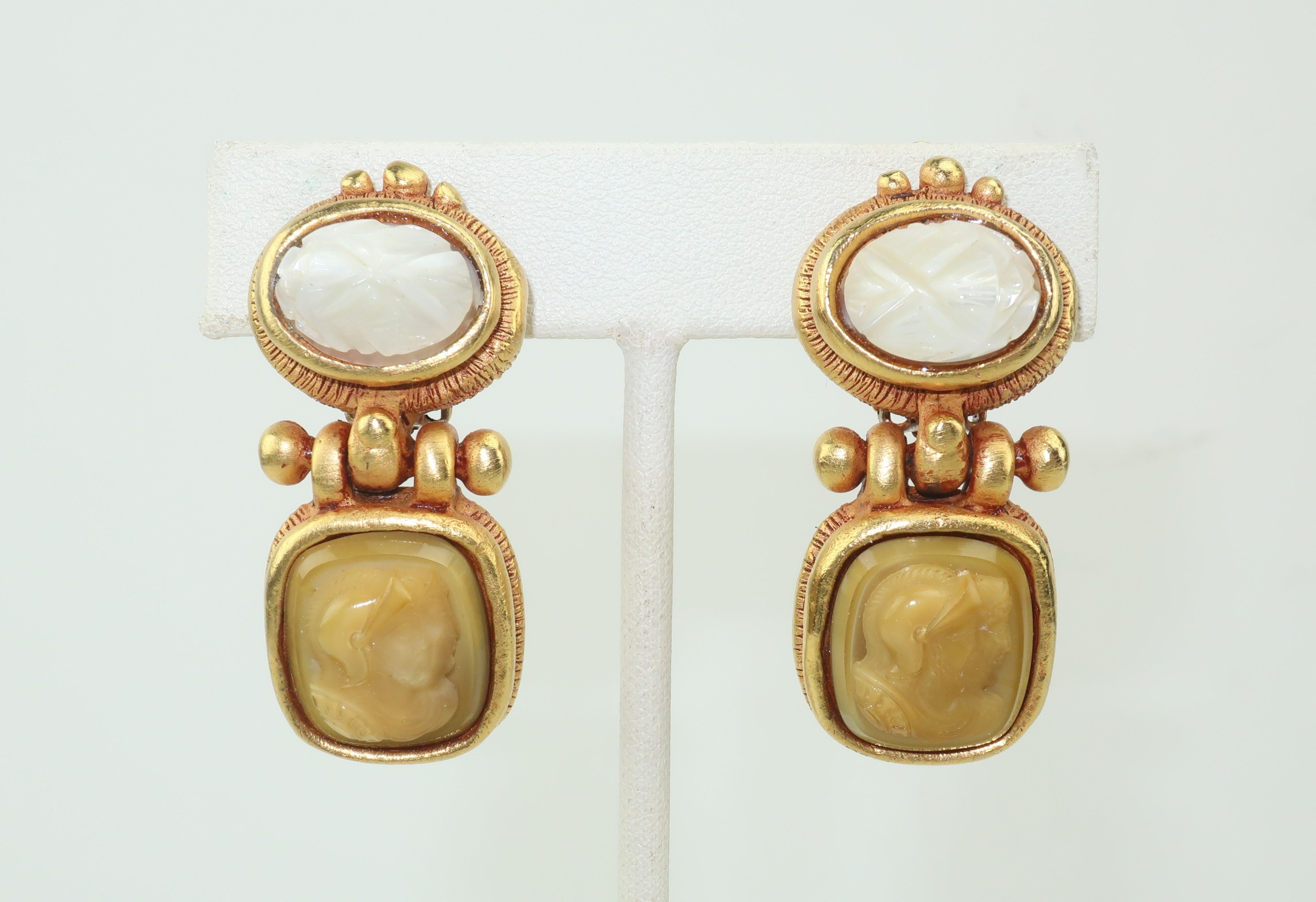 These Lazaro clip on earrings are the perfect blend of modernity and neoclassicism.  A matte gold tone base and drop dangle are finished for an antiquated look and embellished with a carved mother-of-pearl scarab and a beige glass cameo depicting