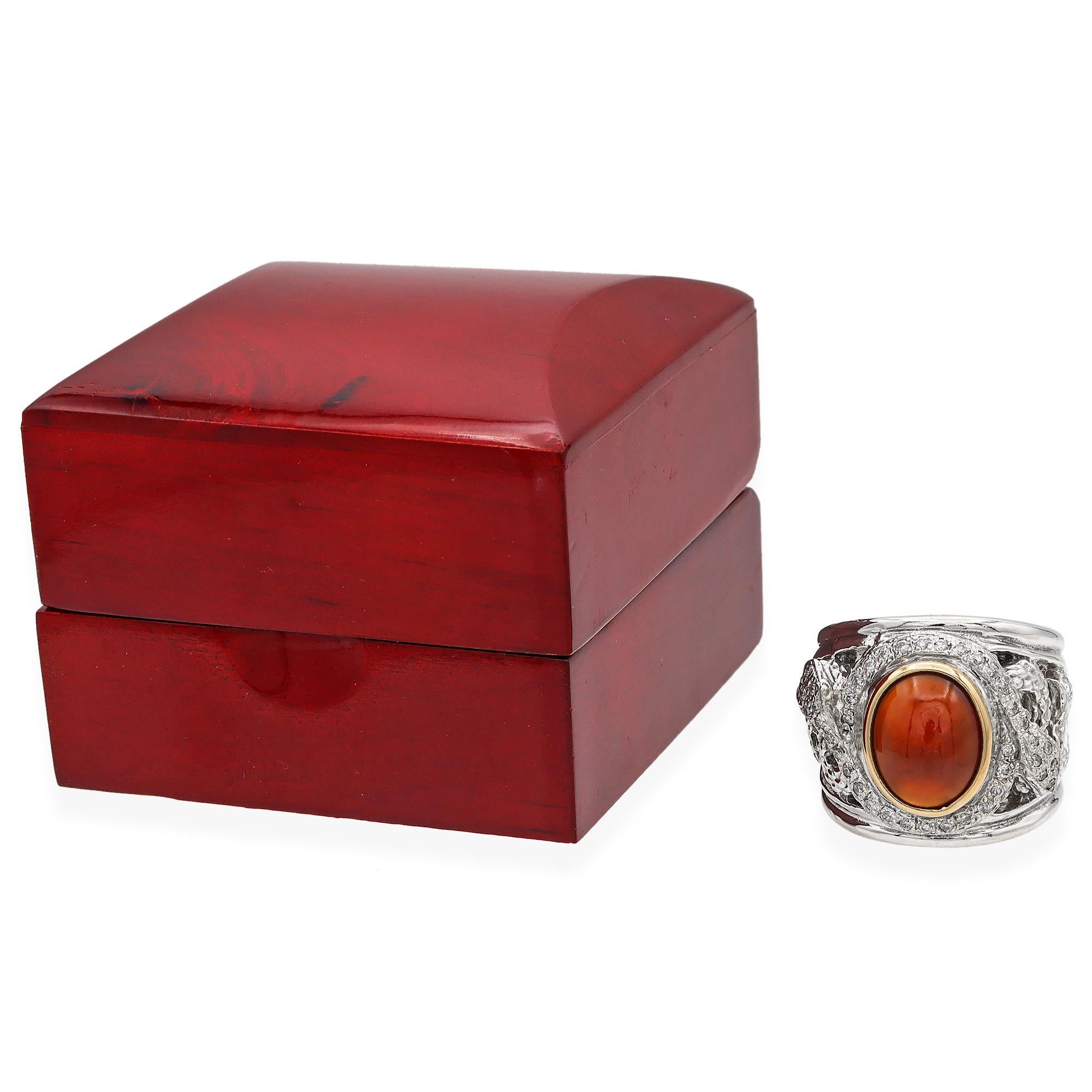 Experience the allure of our exquisite Carnelian and Diamond Band Ring. This captivating piece features a bold carnelian center stone, encircled by a halo of sparkling white diamonds. The intricate design is set in a harmonious blend of 18K gold and