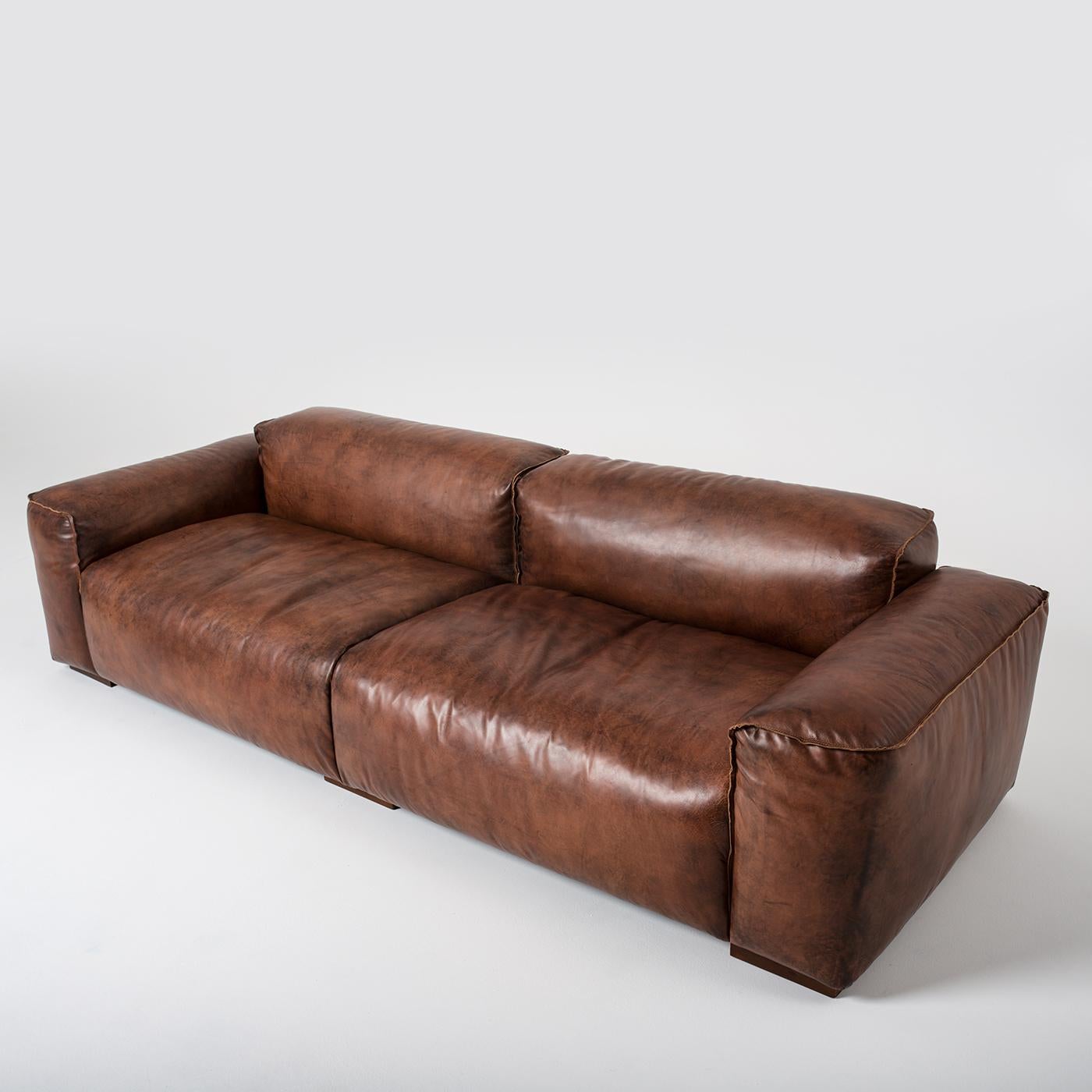 Essential and elegant vintage leather sofa. The raw-cut seams draw the rigorous silhouette creating a meticulous coherence between beauty, simplicity and solidity. The legs are squared in walnut-stained beech.
     