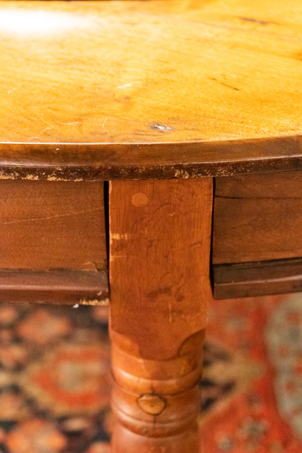 A round, six leg walnut dining table with central lazy Susan platform fitted with turned pull nobs. Each of the turned leg resting on brass casters. Please note of wear consistent with age.