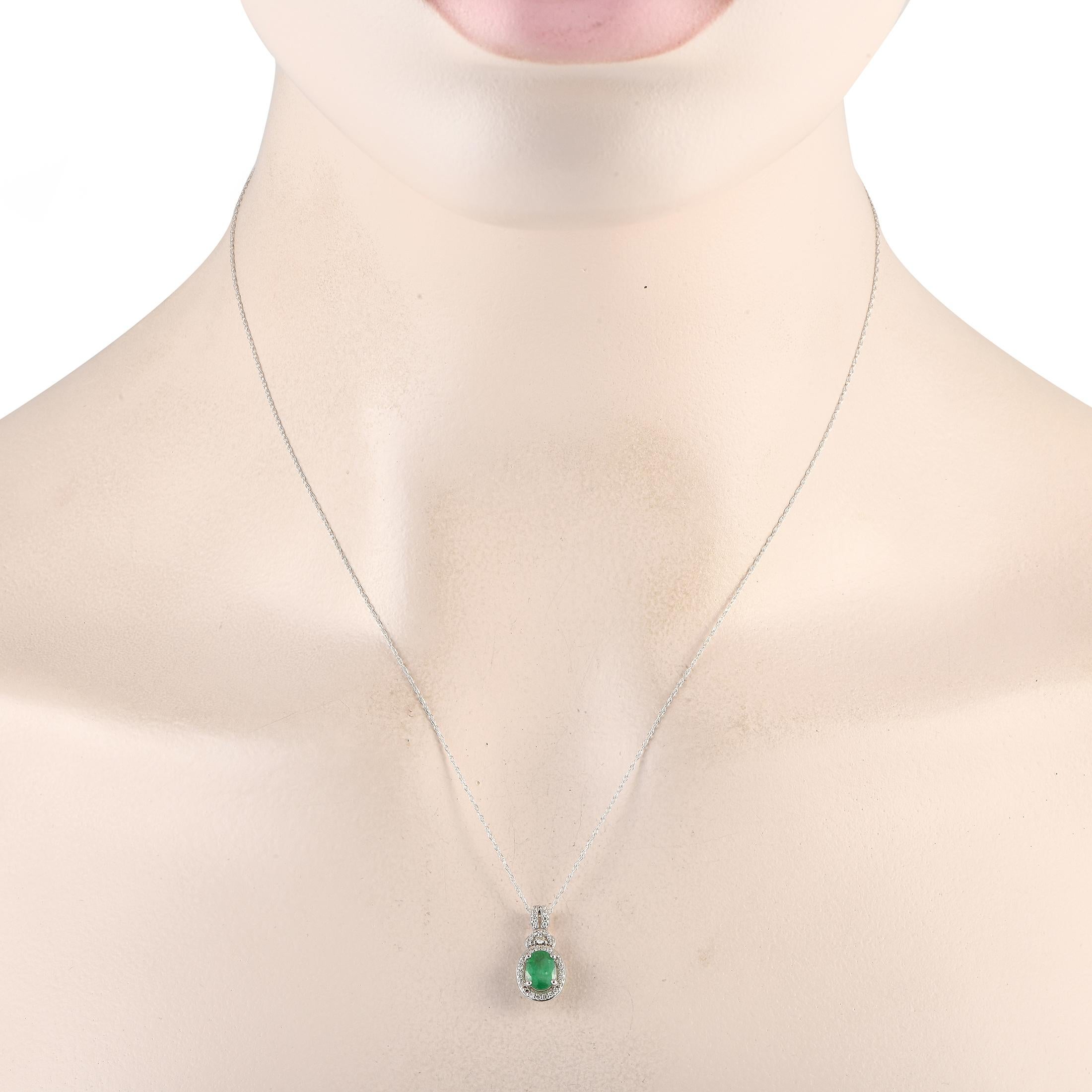 A classic piece that can be your new everyday piece. This 14K white gold necklace features a delicate cable chain measuring 18 inches long. It features a split-style bail traced with diamonds. The gorgeous green emerald stone haloed by an oval frame