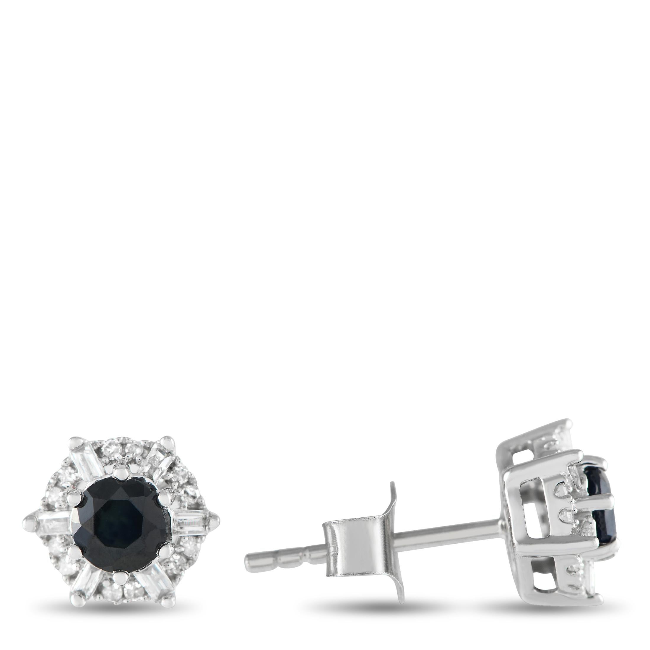 These earrings are petite enough for daily wear. They feature a sapphire center stone held securely by six prongs. An alternating pattern of baguette diamonds and round diamond duos surround the deep blue central gemstone. Each earring measures