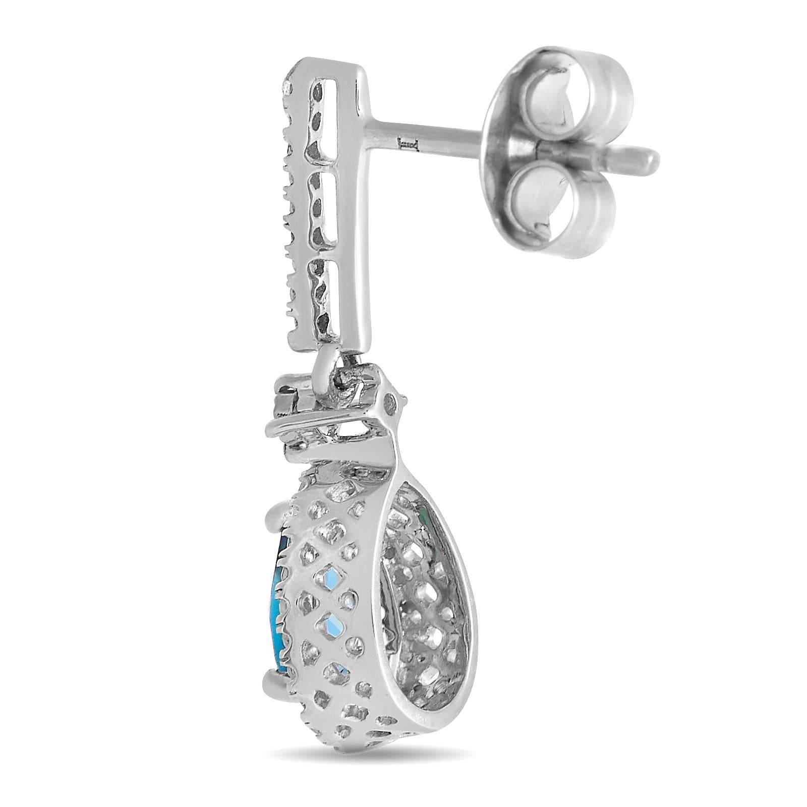 Breathtaking blue topaz gemstones make a statement on these impeccably crafted earrings. Each one features an intricate 14K white gold setting measuring 0.80” long by 0.25” wide. Together, they feature inset diamonds with a total weight of 0.20