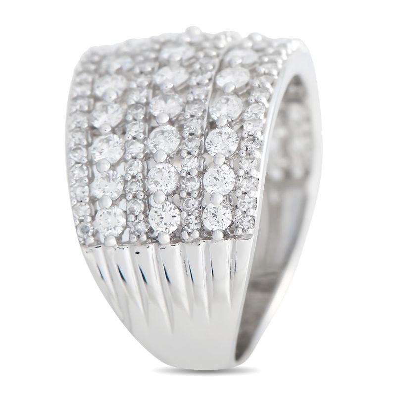 This ring displays a bold yet charming aesthetic. The white gold band has a wide front traced with seven rows of alternating big and small round diamonds on shared prongs. The shank tapers toward the back, with top dimensions measuring 14mm x 25mm.