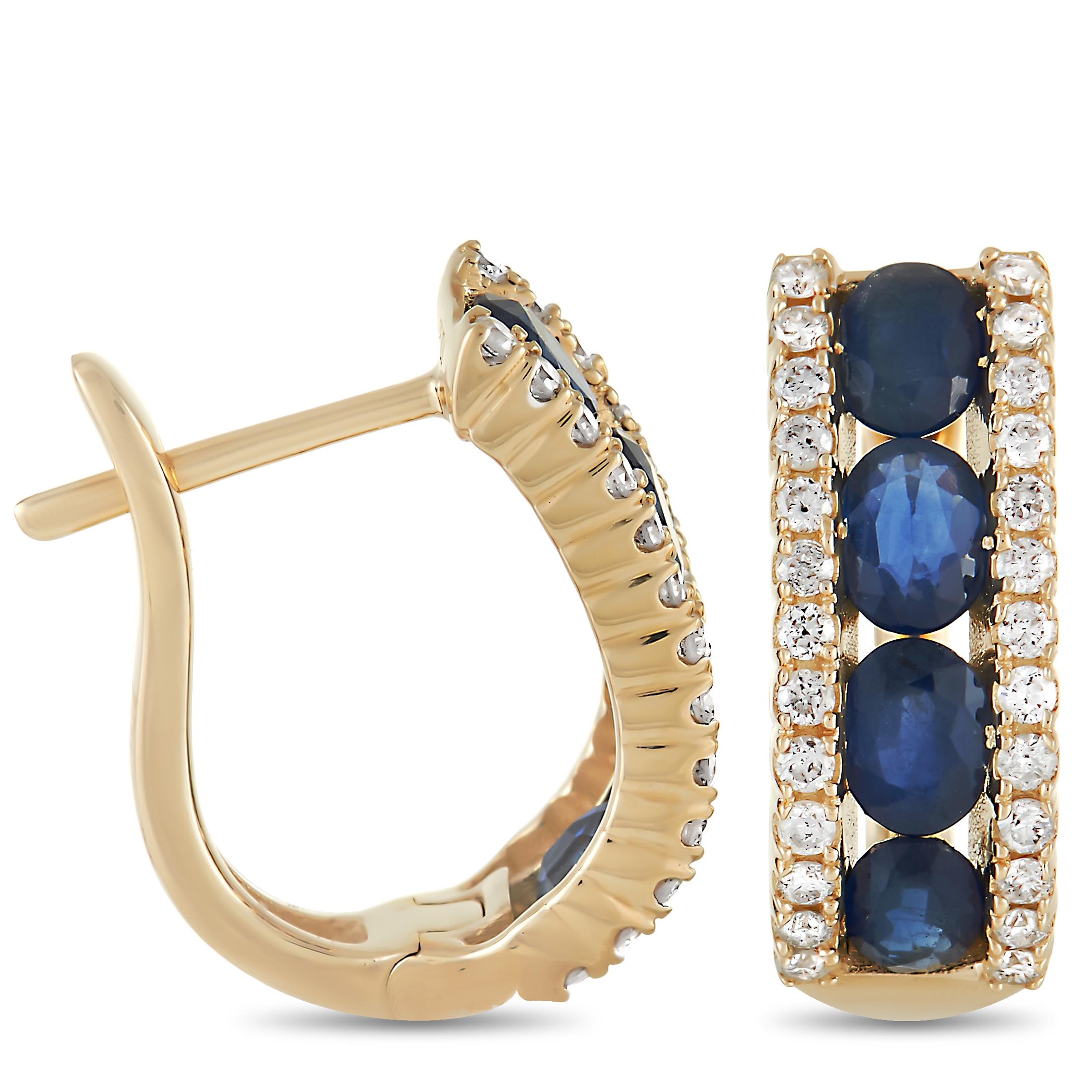 These glamorous earrings are made with 14K yellow gold and are set with a single row of sapphires in the center of each hoop, flanked on either side by a row of small round cut diamonds totaling 0.39 carats. The earrings measure 0.57 inches in