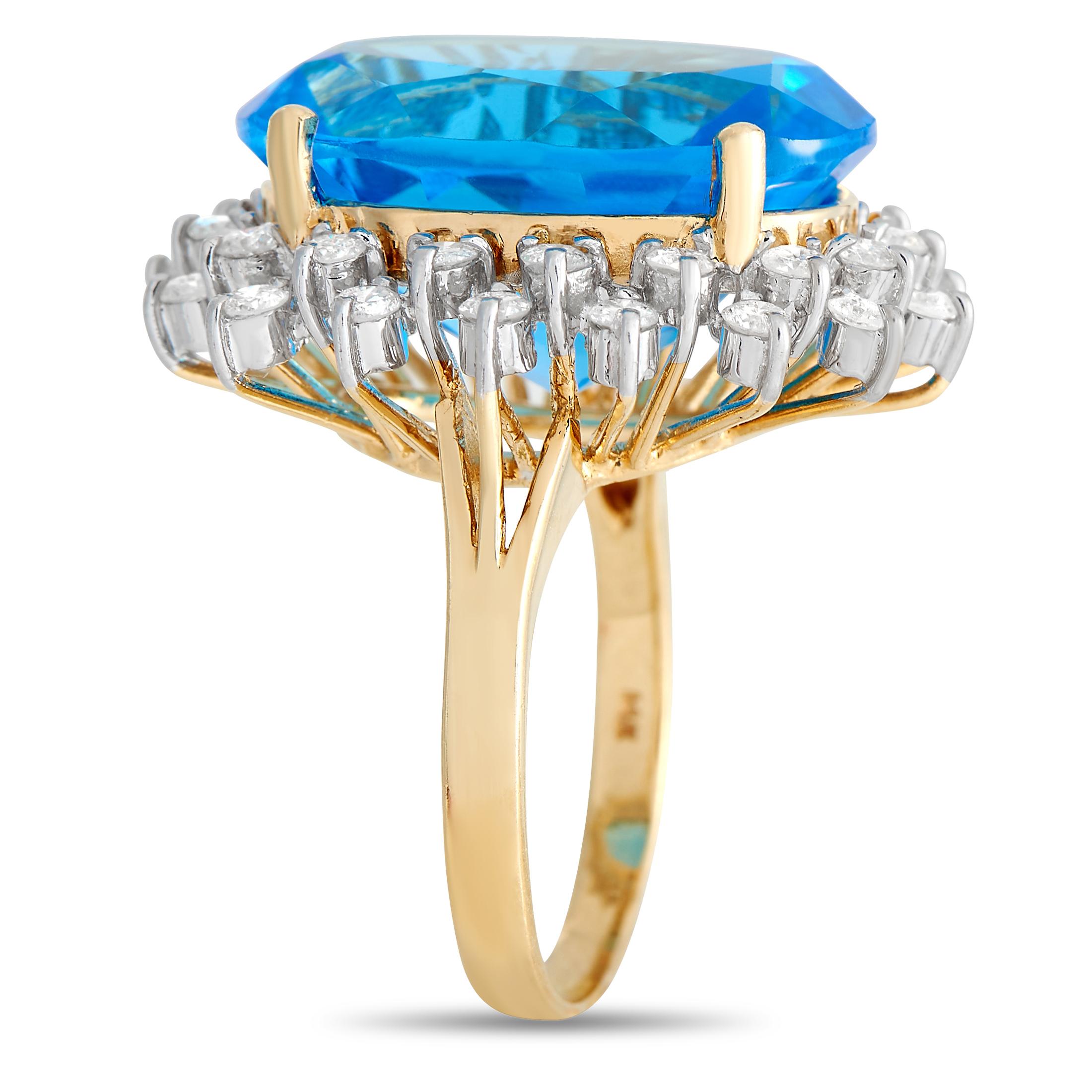 A halo of diamonds totaling 1.10 carats surrounds a large bright blue 12.60 carat topaz gemstone. The 14K yellow setting beautifully compliments the impressive topaz at the center. This jewelry piece is offered in estate condition and includes a
