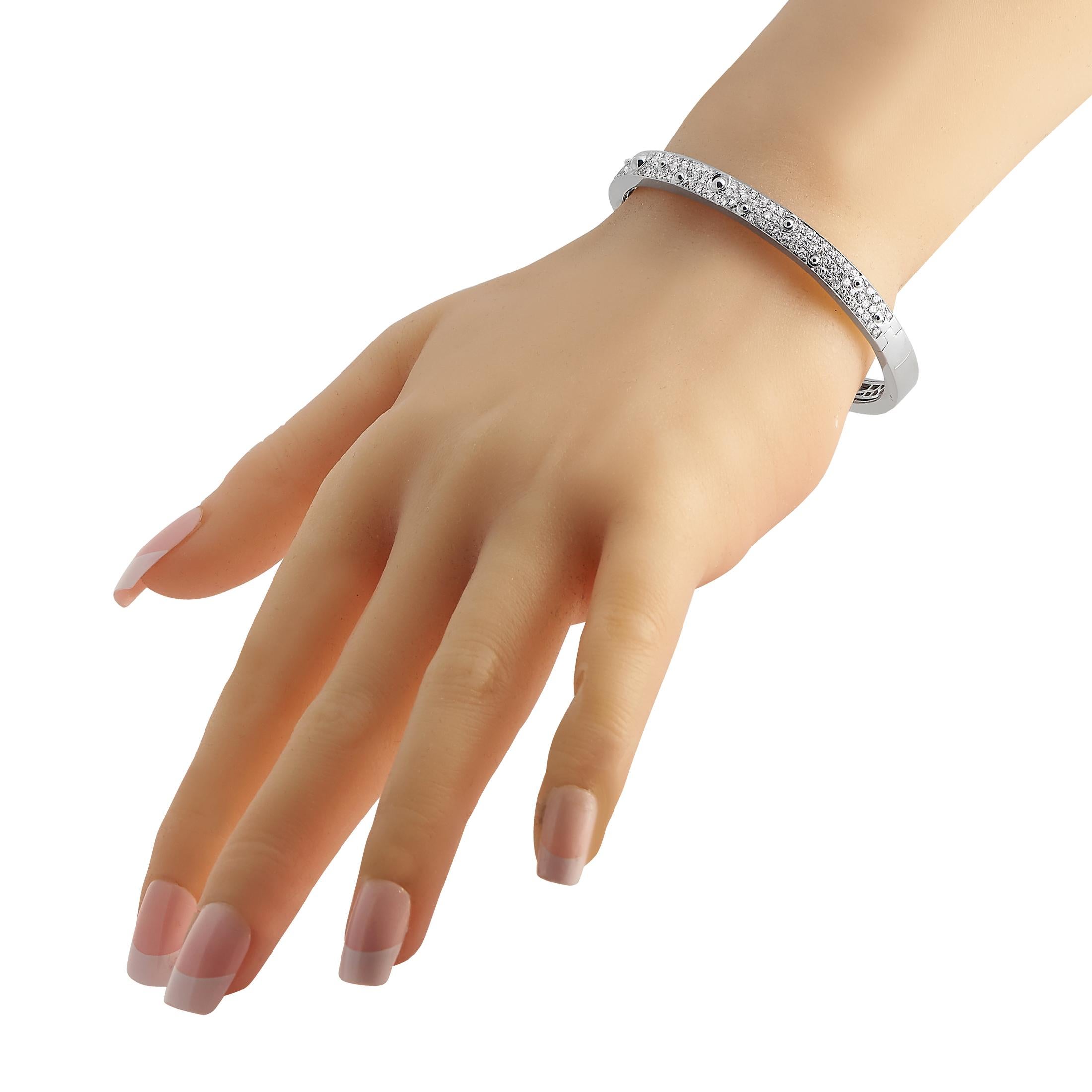 Here is something you can wear when you want to keep things simple and classy yet still sparkly. This solid bracelet is crafted in 18K white gold and has a box tab closure. It features petite round diamonds, punctuated on random spots with domed