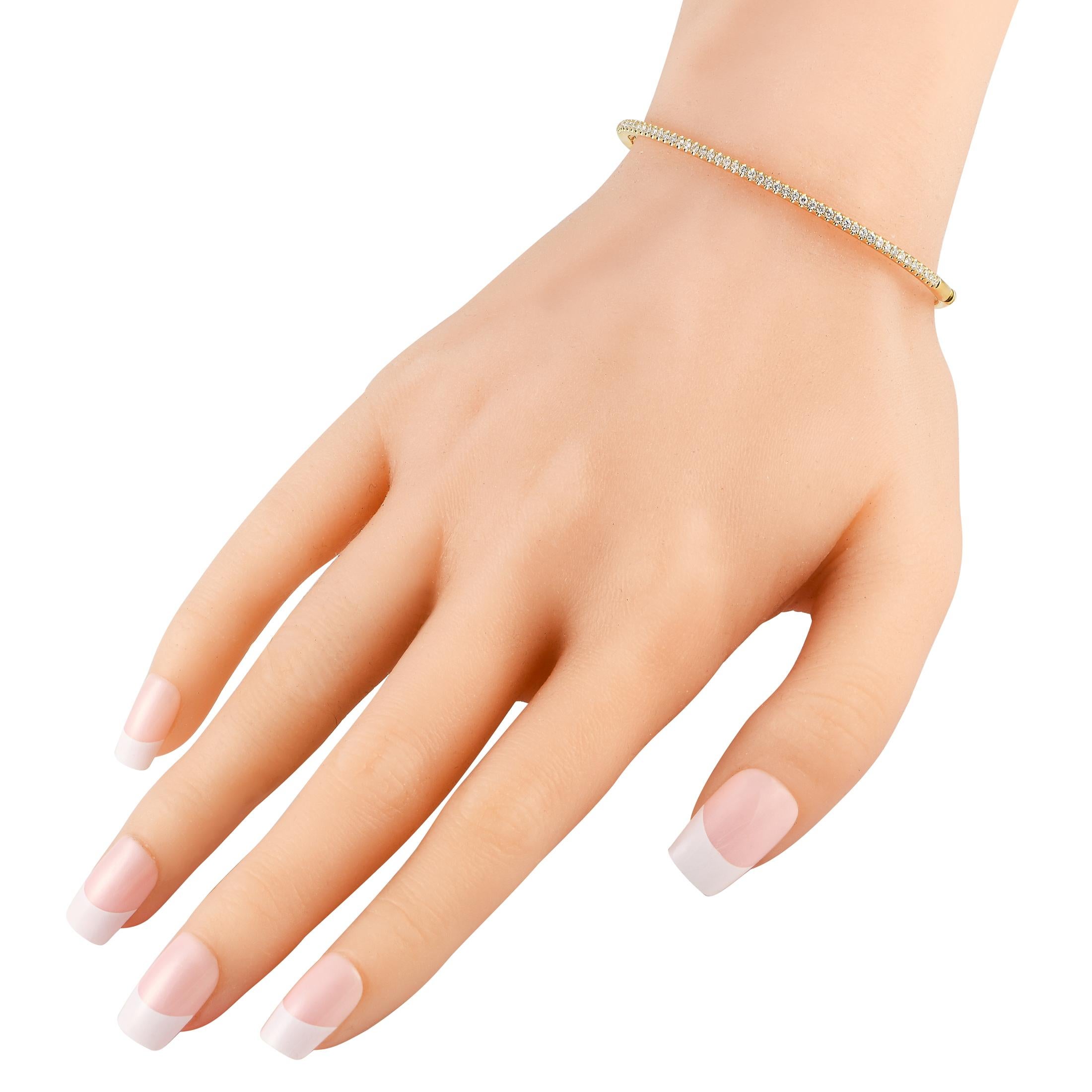 With a slim silhouette and understated sparkle, you can wear this bracelet with anything and everything for an effortlessly chic look. The sleek and slender bangle in solid 18K yellow gold has petite round diamonds running along half of its