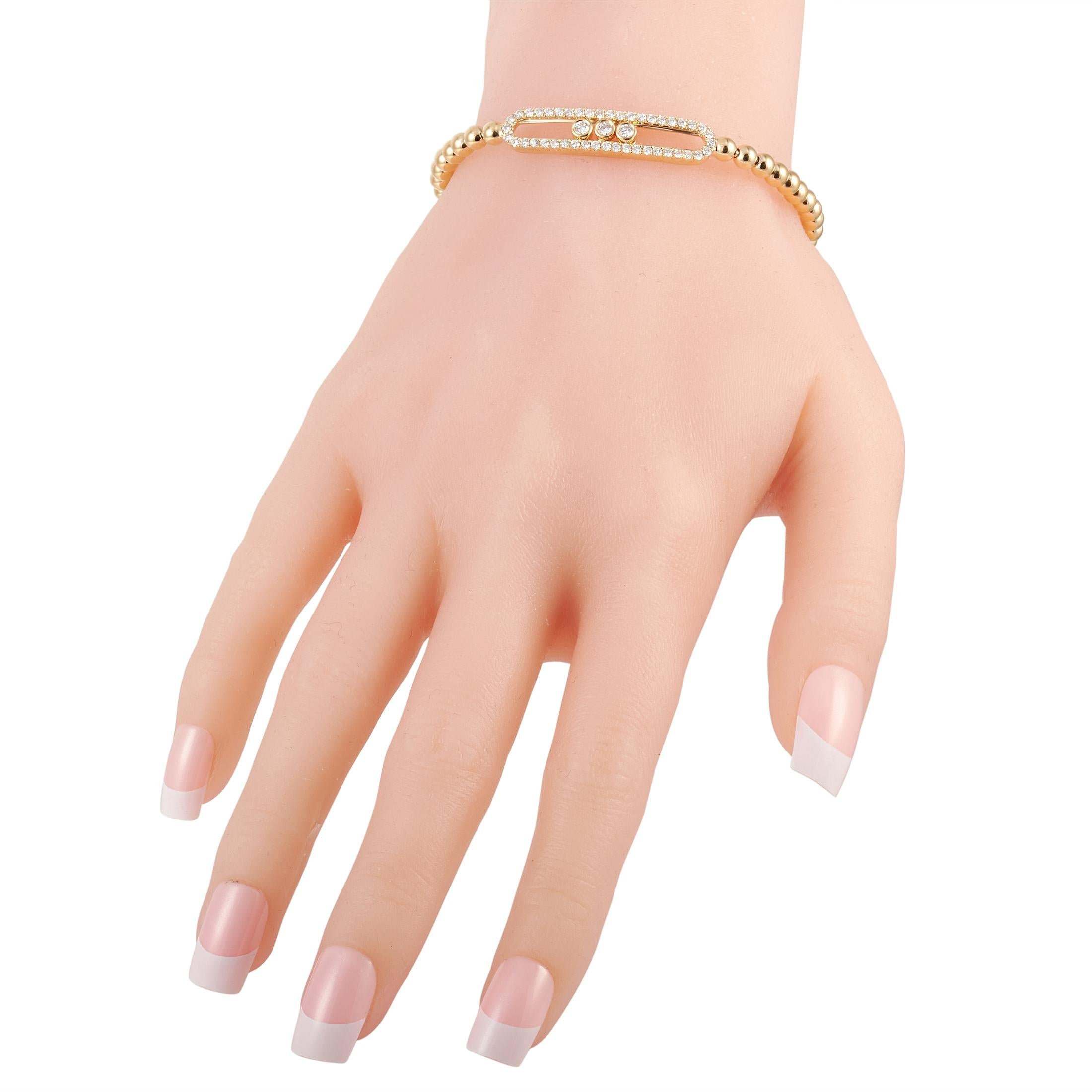 This beaded 18K yellow gold bracelet features an oval ornament lined with diamonds and dotted with a trio of bezel-set diamonds. This dainty and feminine wrist accessory sparkles with just a hint of glitter from its 0.80 carat white diamond