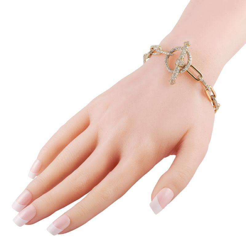 Mühelos, ausgefallen und für die Ewigkeit - dieses Gliederarmband mit Knebelverschluss und Diamantverzierungen darf in Ihrem Schmuckkästchen nicht fehlen. Dieses 8,25 cm lange Armband besteht aus einer kühnen Kette aus 18 Karat Gelbgold, die mit