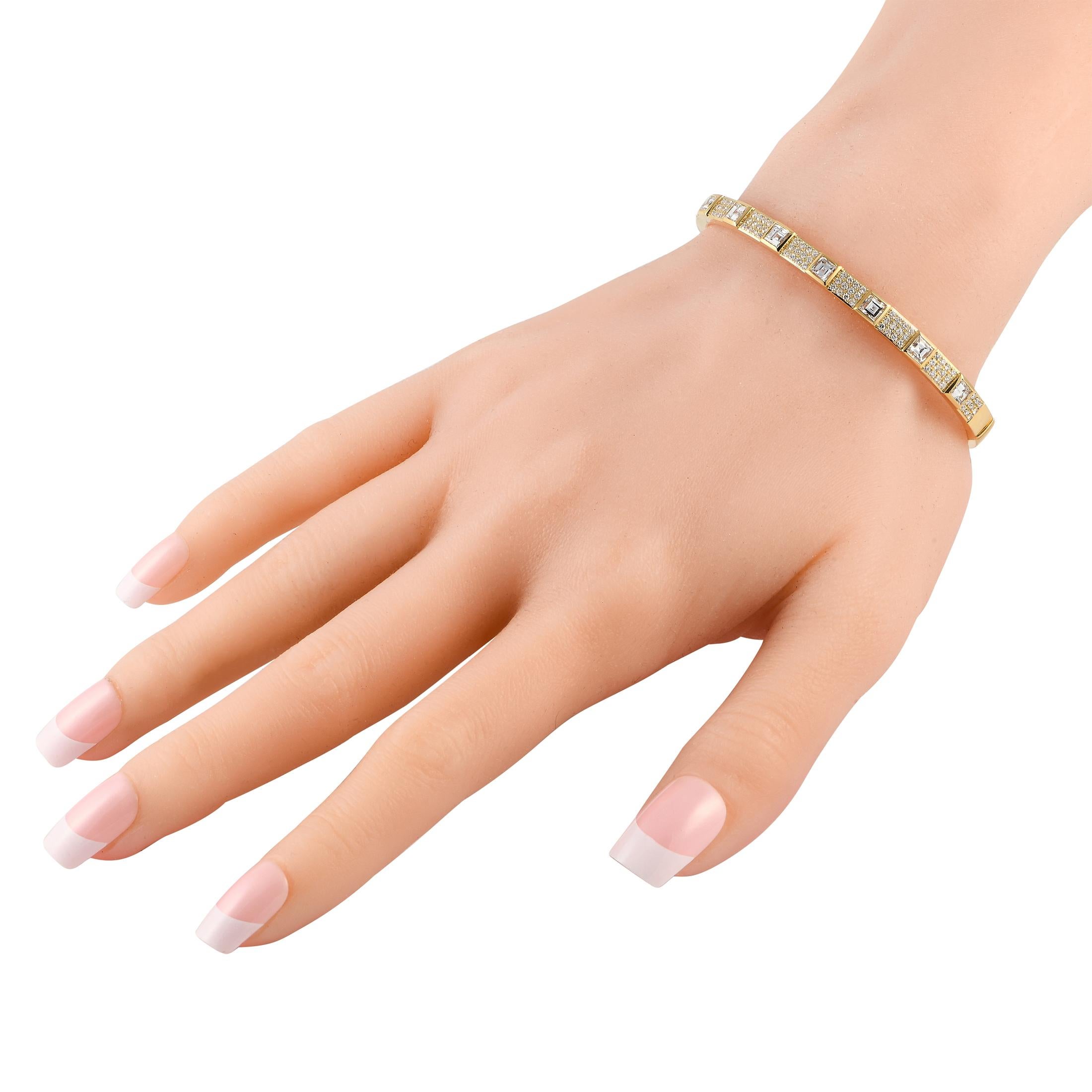 Whether worn with a classic button-down or a formal gown, this diamond bracelet can elevate an outfit. This yellow gold bangle shimmers with a pattern of alternating step-cut diamonds on square bezels and paved diamond clusters. Easy to put on and