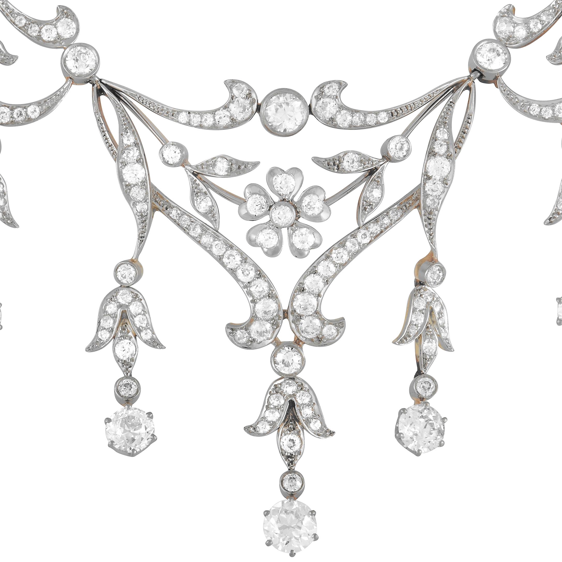 This exquisite antique necklace features a distinct sense of old fashioned opulence. An intricate platinum setting accented by hints of 18K yellow gold provides the perfect foundation for this captivating piece of jewelry. Diamonds with a total