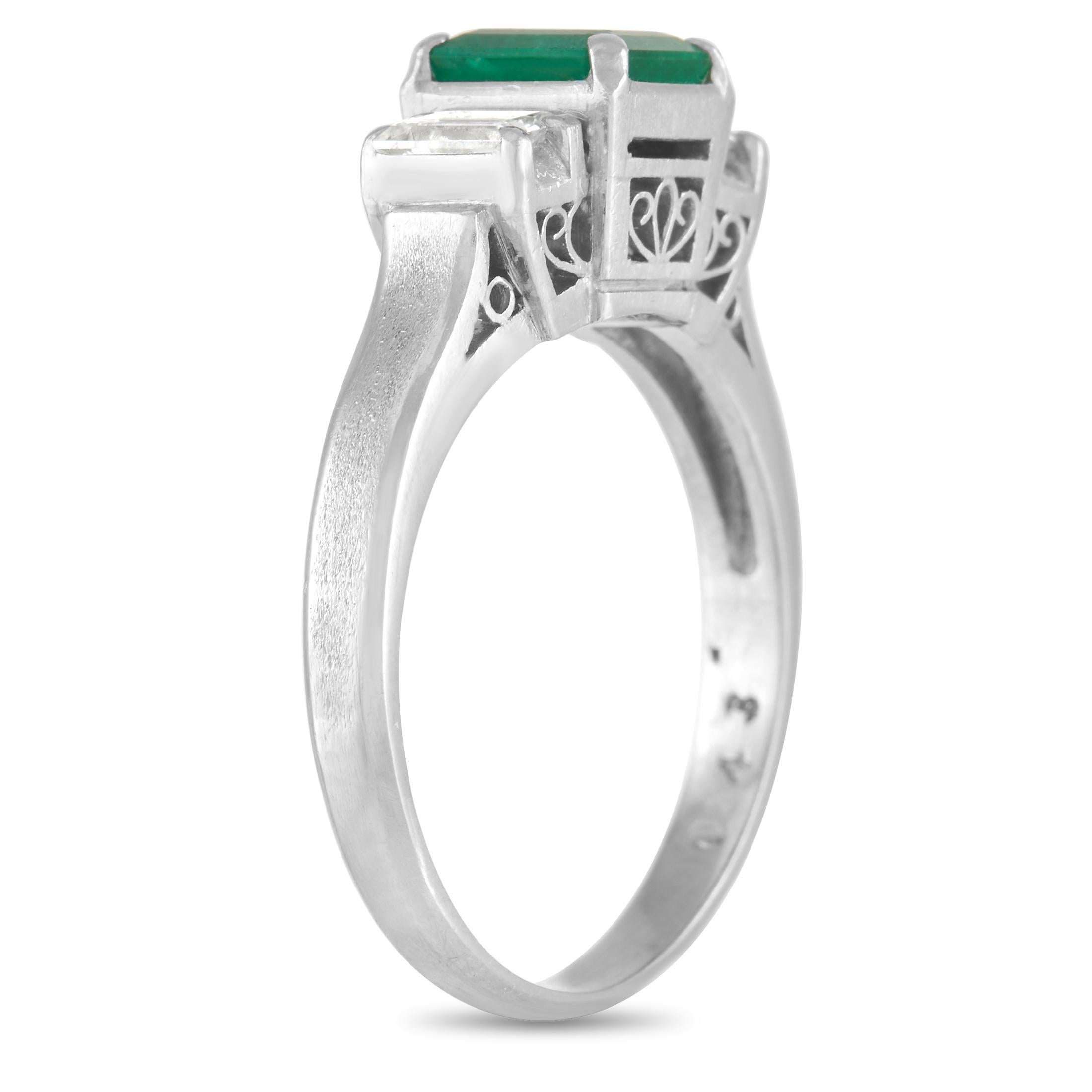 This estate ring possesses a certain old fashioned elegance. At the center of the platinum setting, you’ll find a 0.43 carat emerald gemstone with a captivating green color. It’s flanked by a pair of step-cut diamonds that together total 0.30
