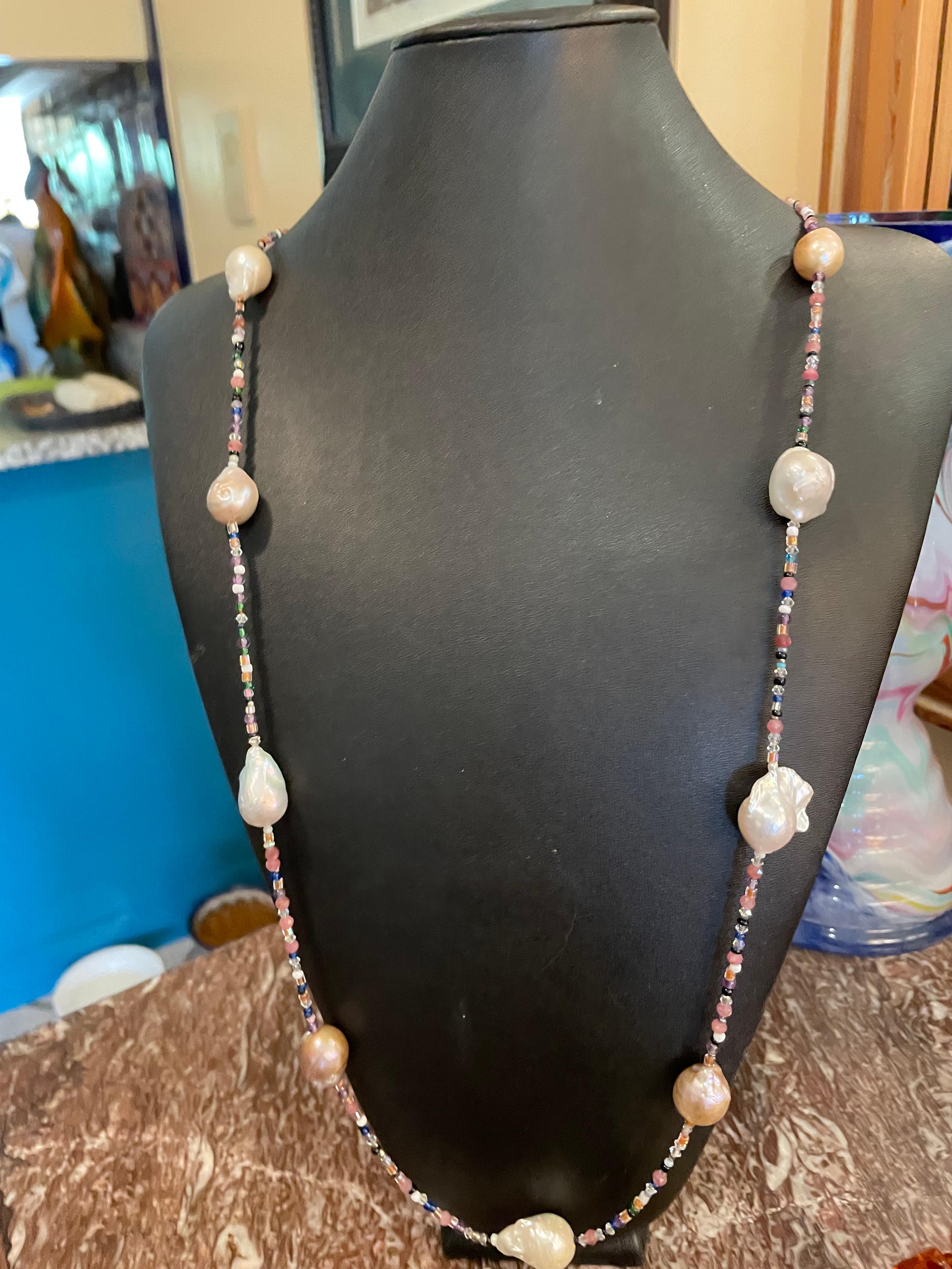 Lorraine’s Bijoux offers a luscious rope necklace of large white and blush freshwater Baroque Pearls. This wonderful long rope is perfect with any outfit from jeans and a Tee to a cocktail dress. The lovely tiny crystals are multi colored and add