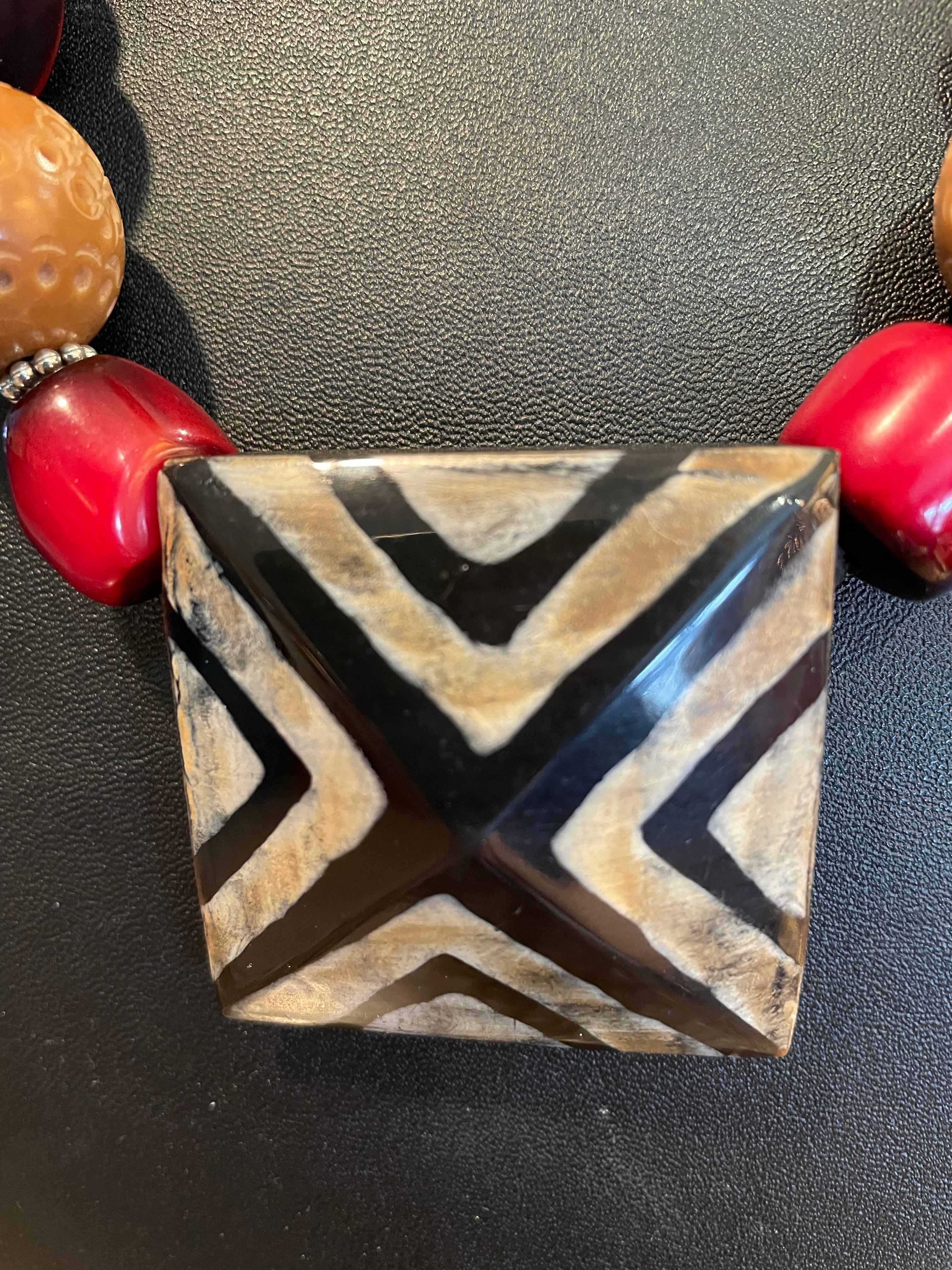 LB offers a one of a kind, handmade, 
Large hand painted bone pendant, necklace. A stunning string of Indian resin,
Sterling Silver and hand carved Chinese stone beads beautifully enhance the pendant. This necklace has a tribal chunky character and