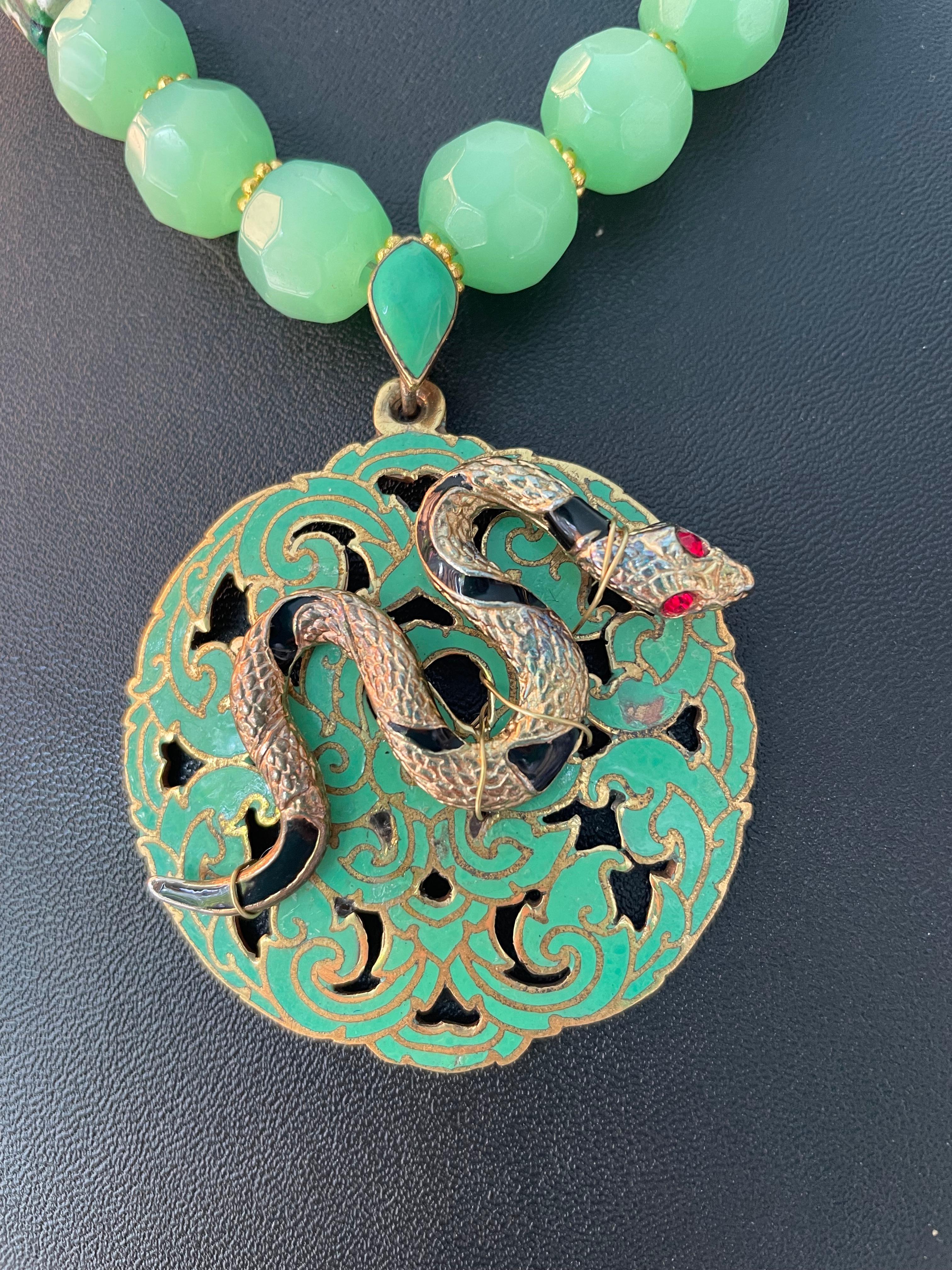 Lorraine’s Bijoux has on offer a 60’s Green Enamel floral motif pierced Brass Pendant. 
Green vintage Peking glass faceted beads, Brass Tibetan beads, Venetian glass Mille Fiore beads, Tibetan brass beads, enhance this unusual centerpiece. This is