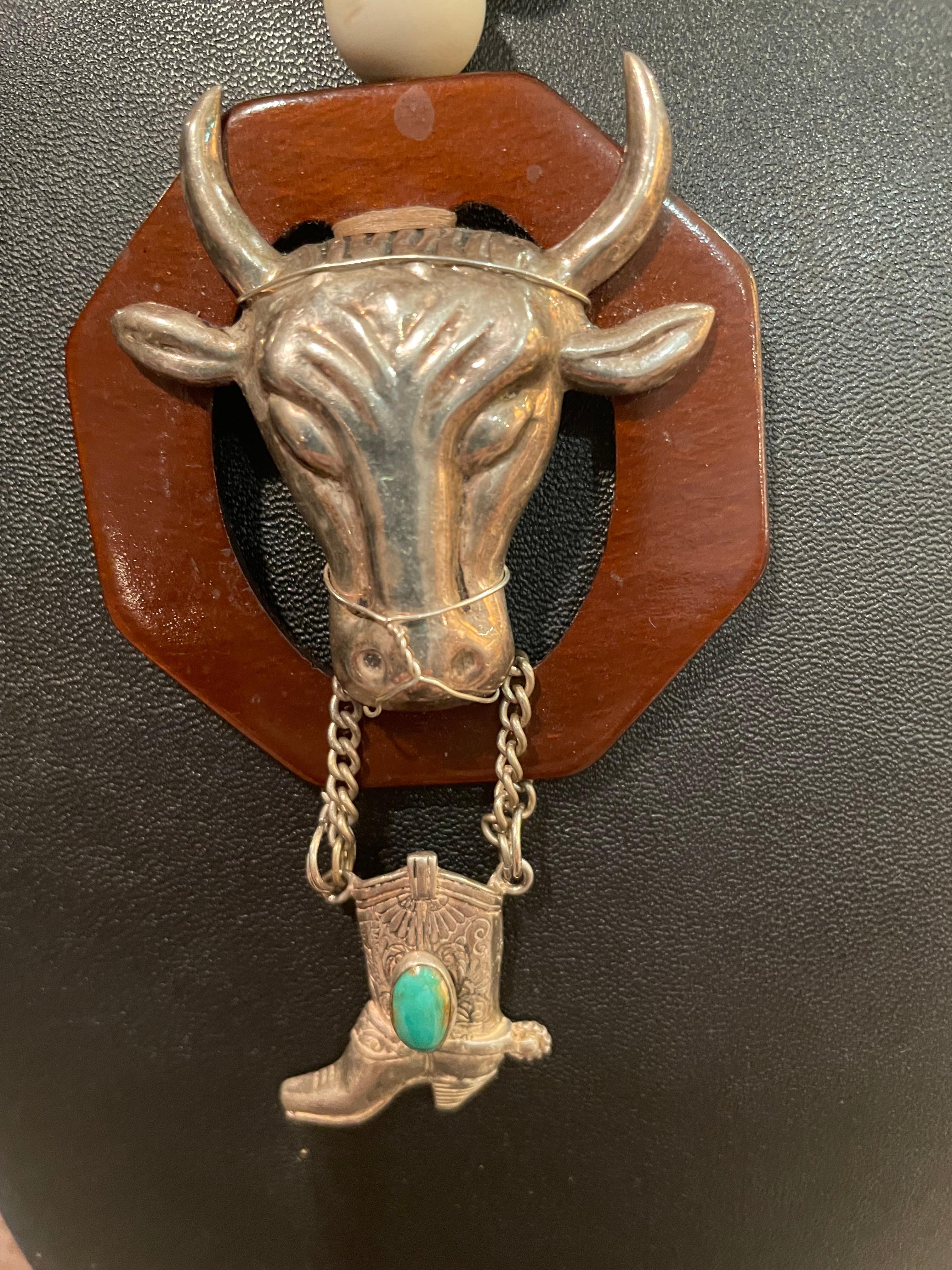 LB offers a stunning, handmade, one of a kind, Sterling Silver and Bakelite pendant necklace. The Sterling Silver Bull and cowboy boot are mid 20th Century brooches that have joined to create a gorgeous centerpiece for this unusual creation. Very