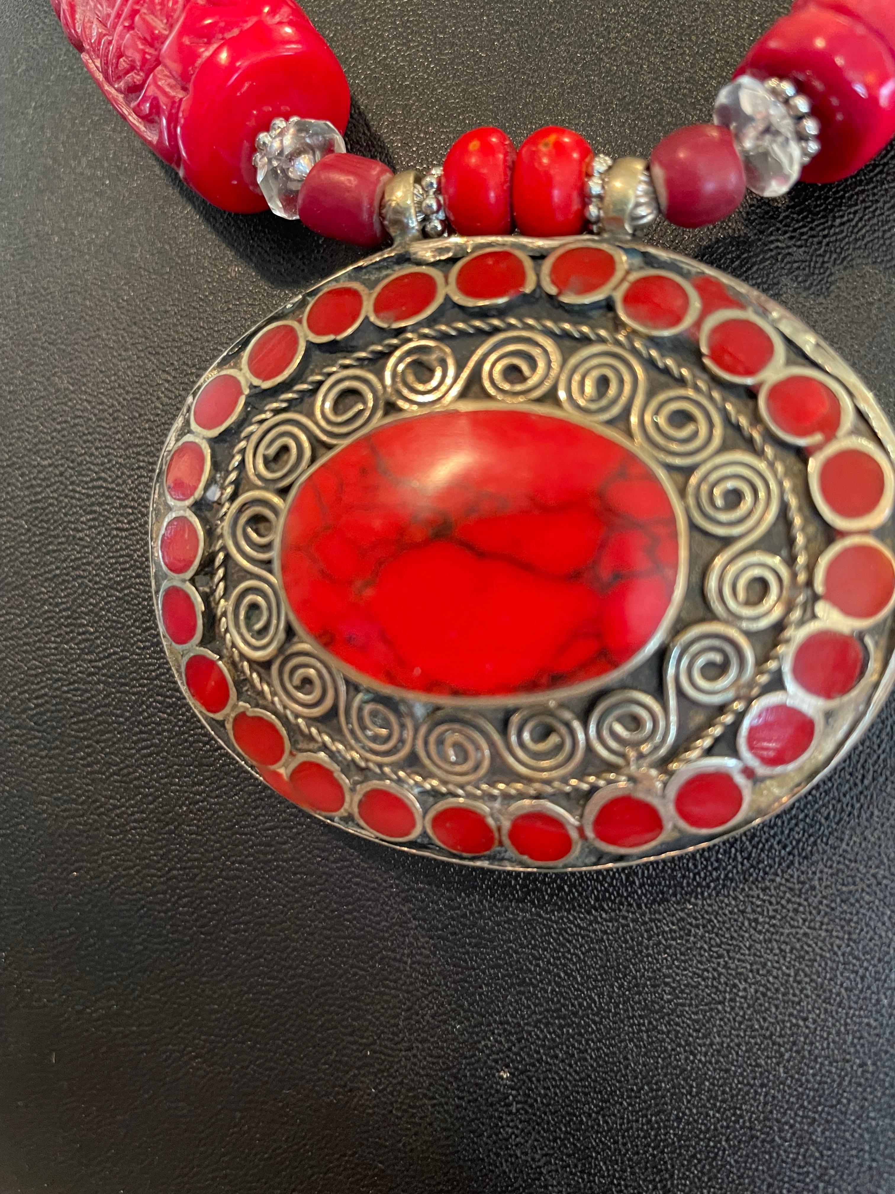 Lorraine’s Bijoux offers a Tribal Coral, Silver inlaid Tibetan pendant with intricate silver wirework. This necklace is a stunning casual look with carved coral beads, large chunks of red Bamboo Coral, coral inlaid Tibetan silver chased beads, red