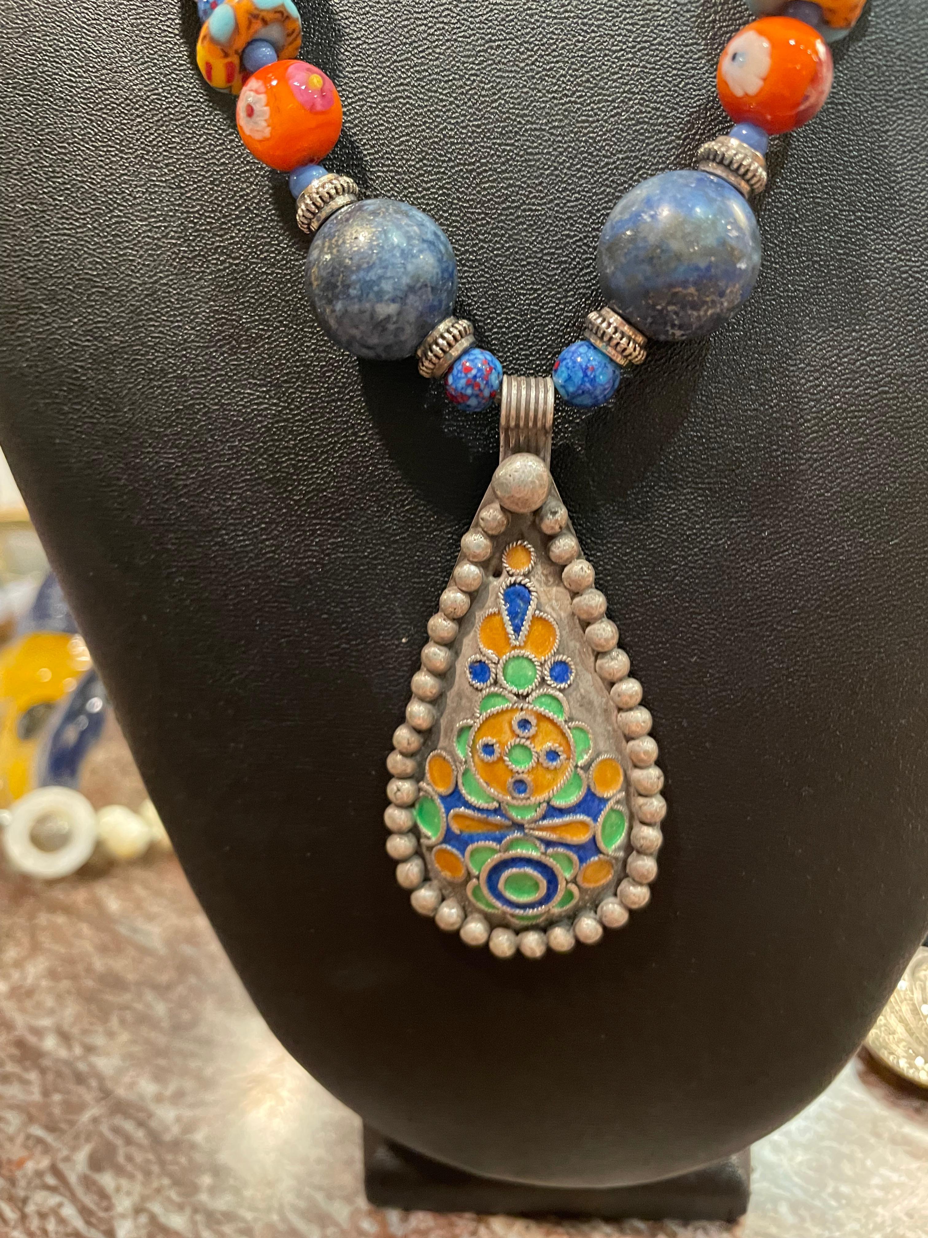 LB offers a handmade; one of a kind, stunning tribal necklace. I purchased this pendant in Morocco several years ago and it has hand applied enamel in green, blue, and gold. This pendant is completely handmade with silver based wire and granulation.