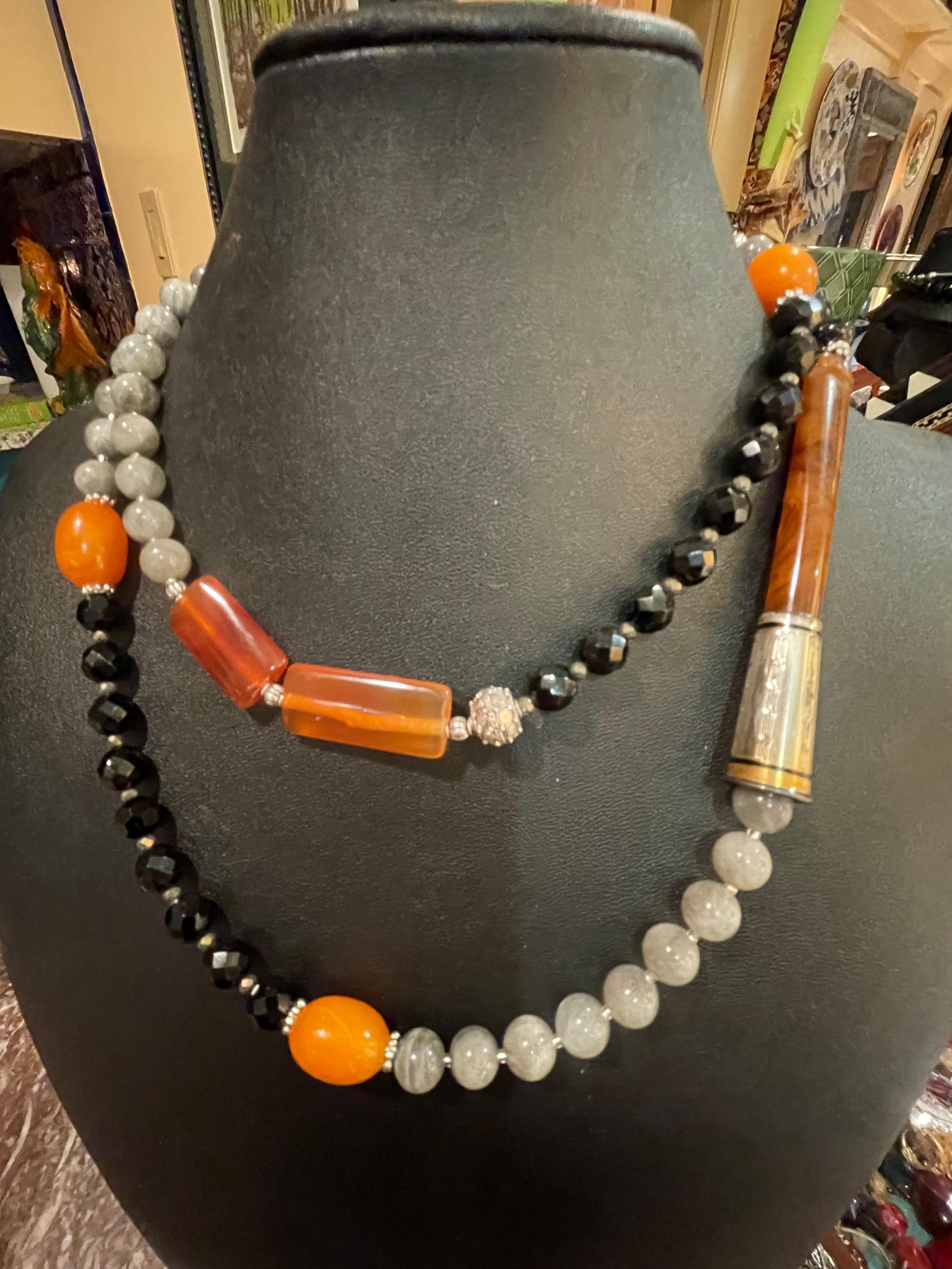 LB offers a one of a kind, handmade, Art Deco style vintage cigarette holder necklace. The combination of faceted black onyx, labradorite, carnelian, Amber Bakelite, and sterling silver make this stunning piece perfect for just about any occasion.