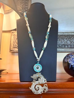 LB propose un pendentif en pierre chinoise sculptée, une broche en émail et des perles en os et turquoise